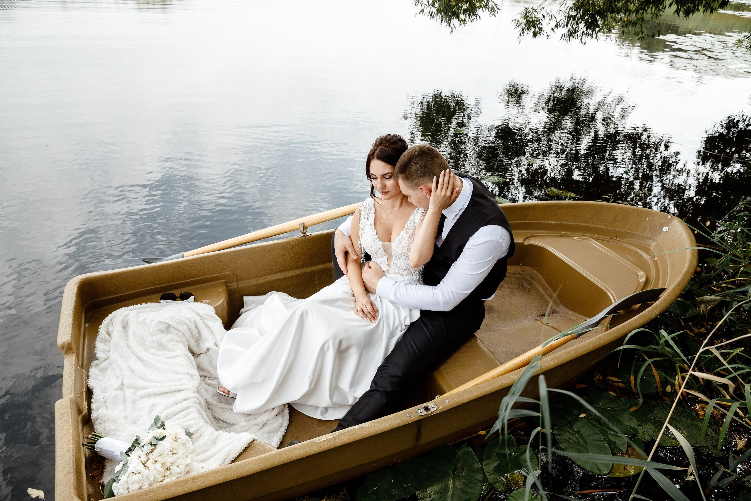 Жених и невеста сидят в лодке на природе