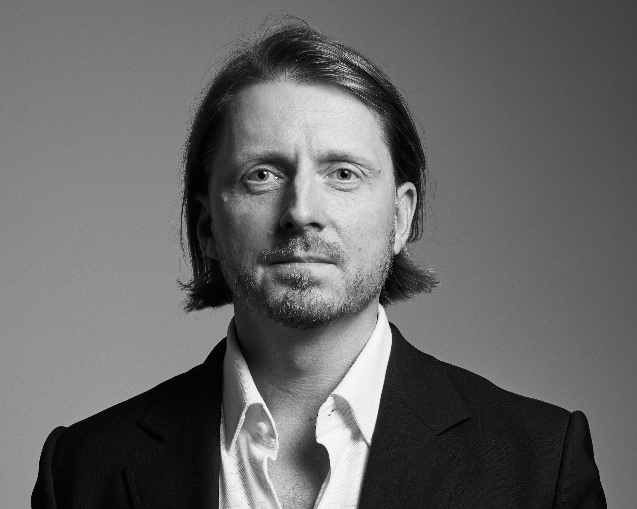 Black and white business portrait of a confident man in a suit on a dark studio background