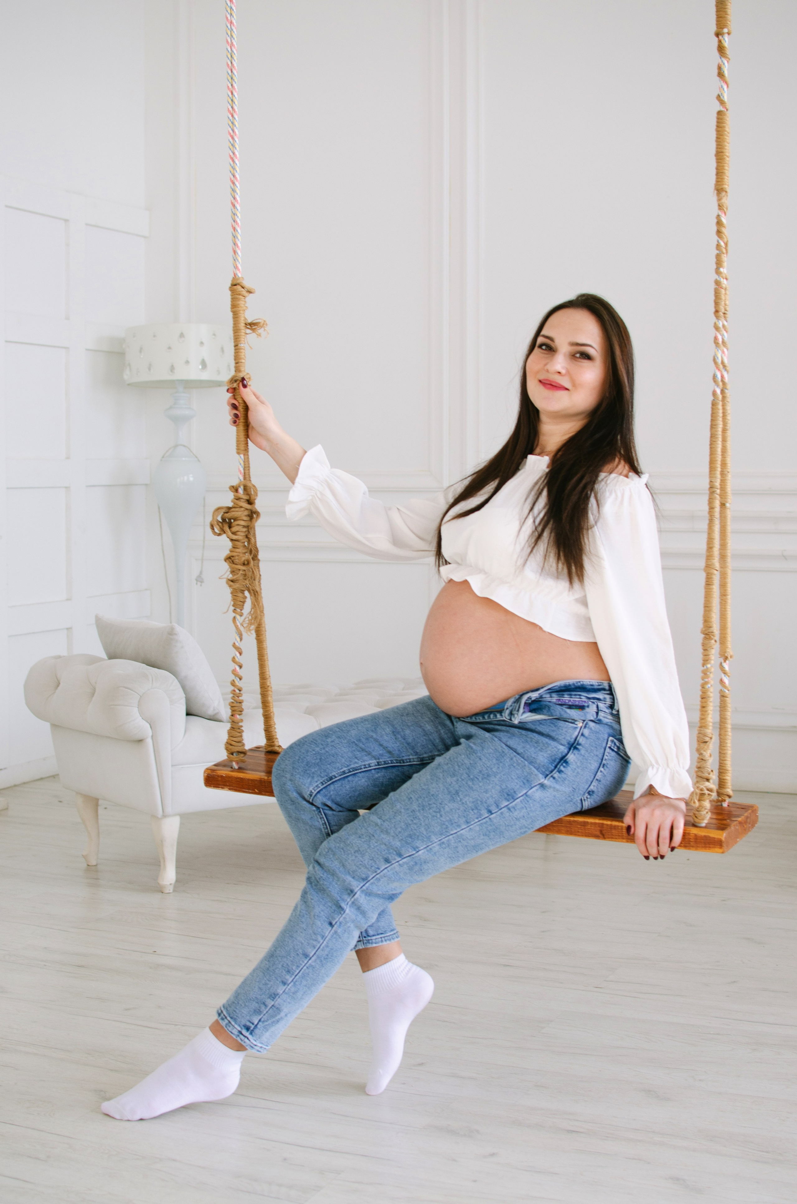 Девушка в ожидание беременности на качелях