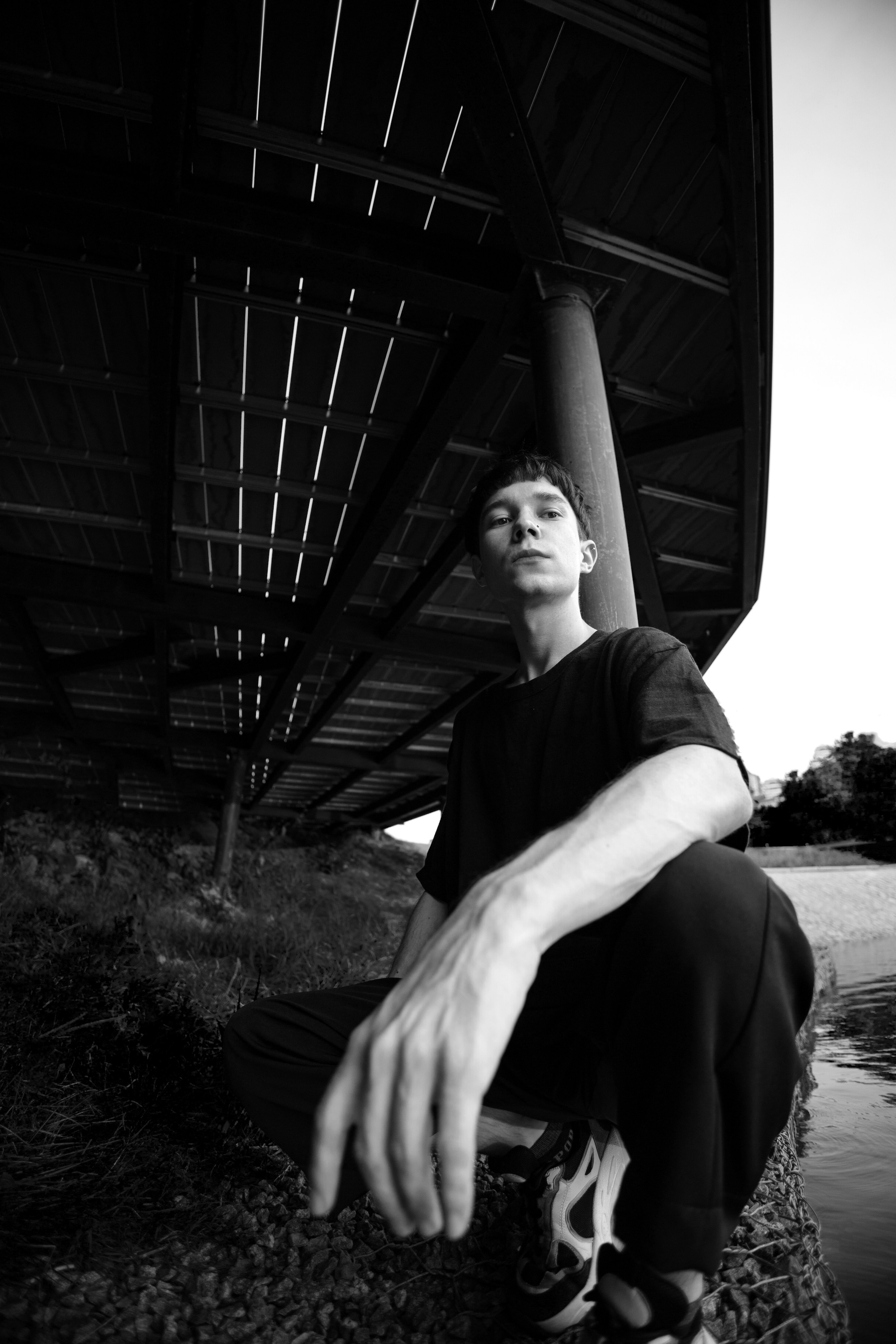 Мужчина сидит на корточках на черном  фоне.