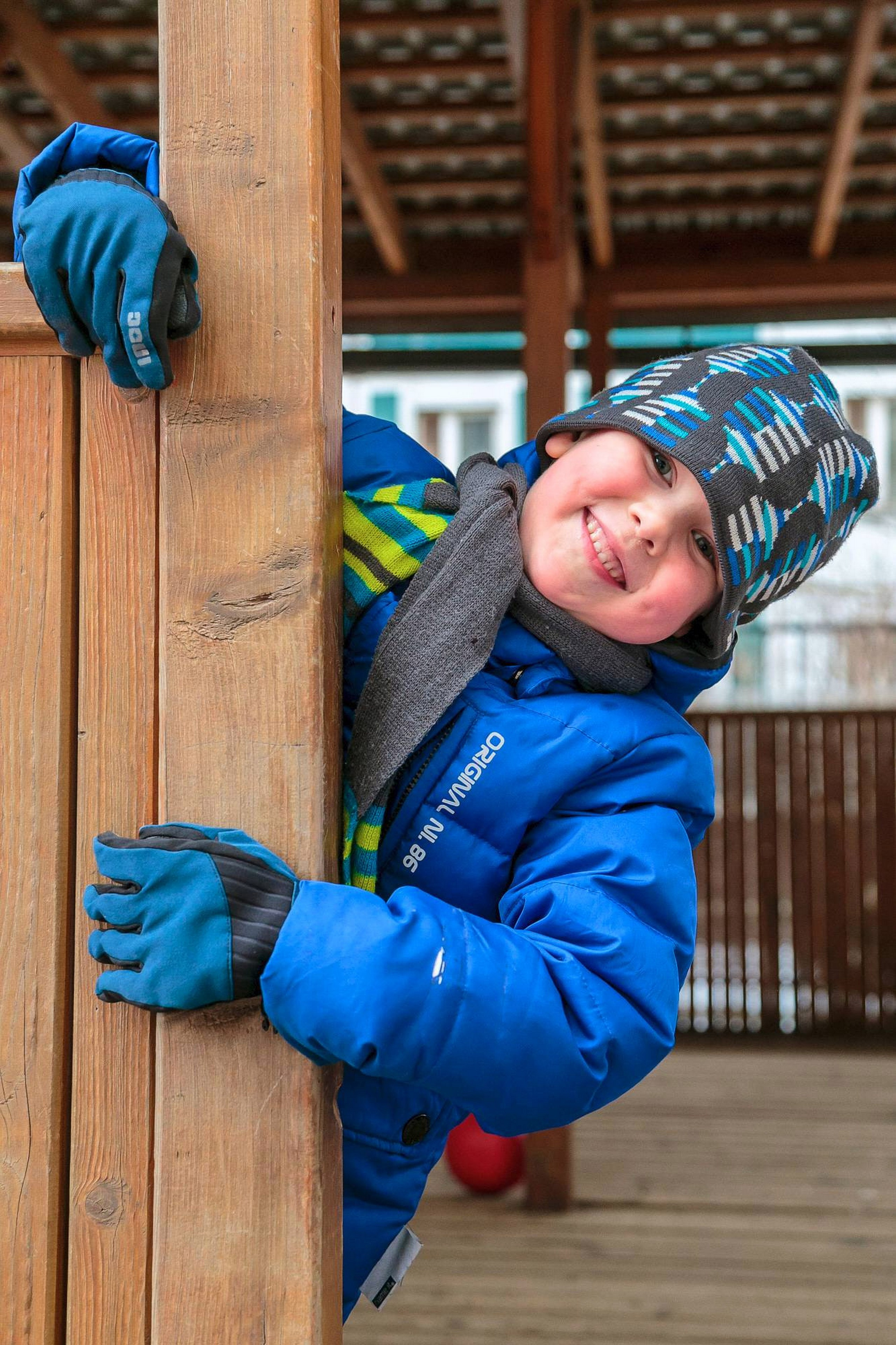 мальчик на прогулке играет в прятки и фотографируется