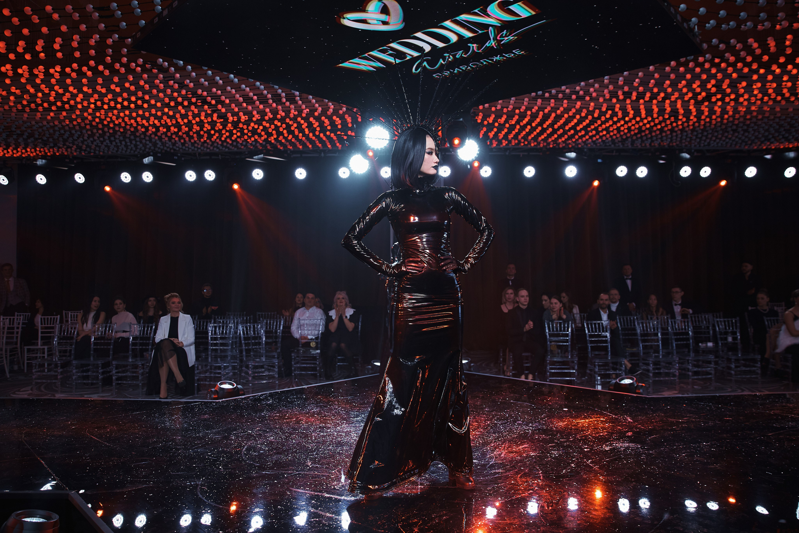 Девушка в черном платье стоит на сцене