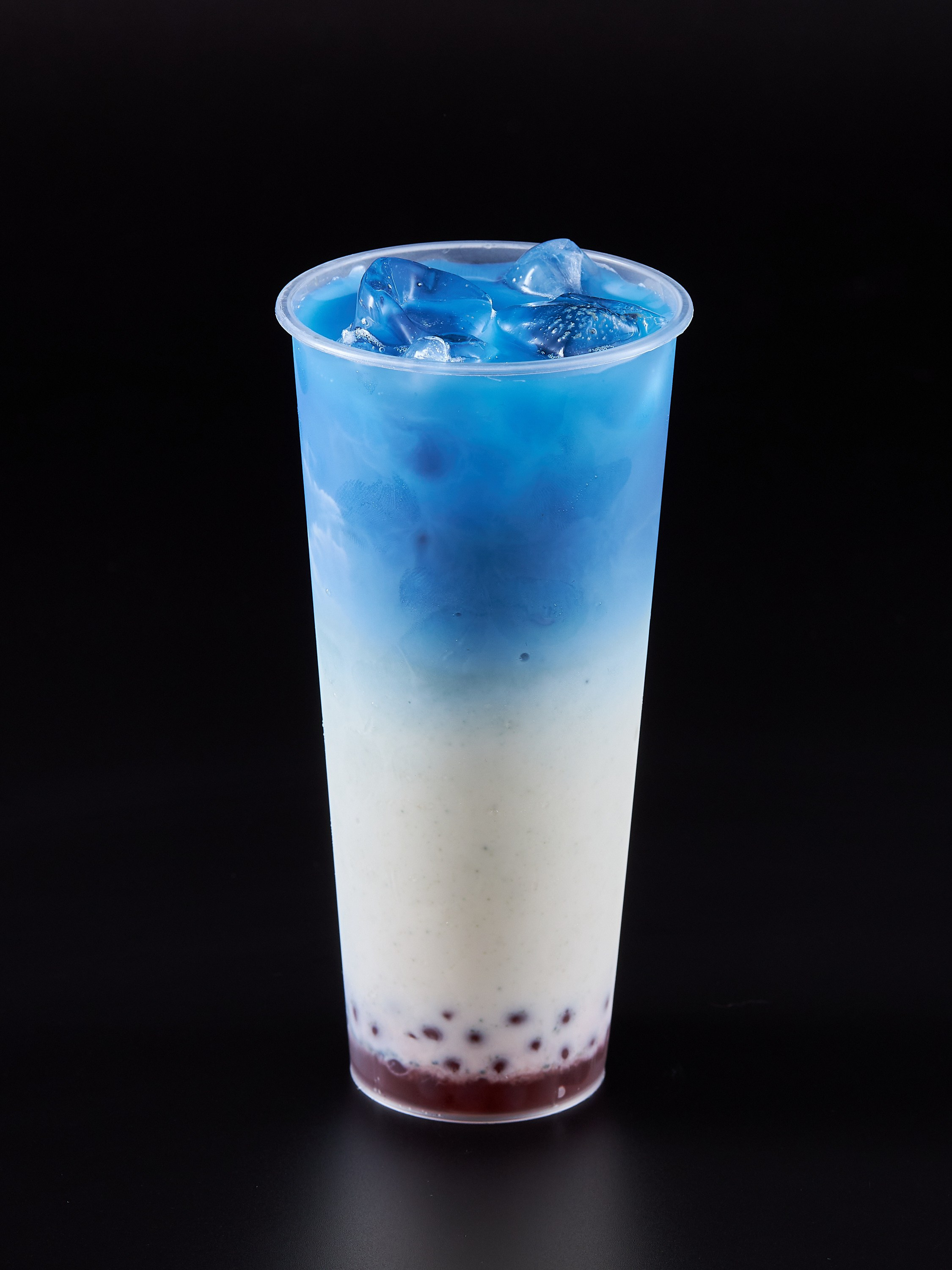 Коктейль в пластиковом стакане синего цвета на черном фоне