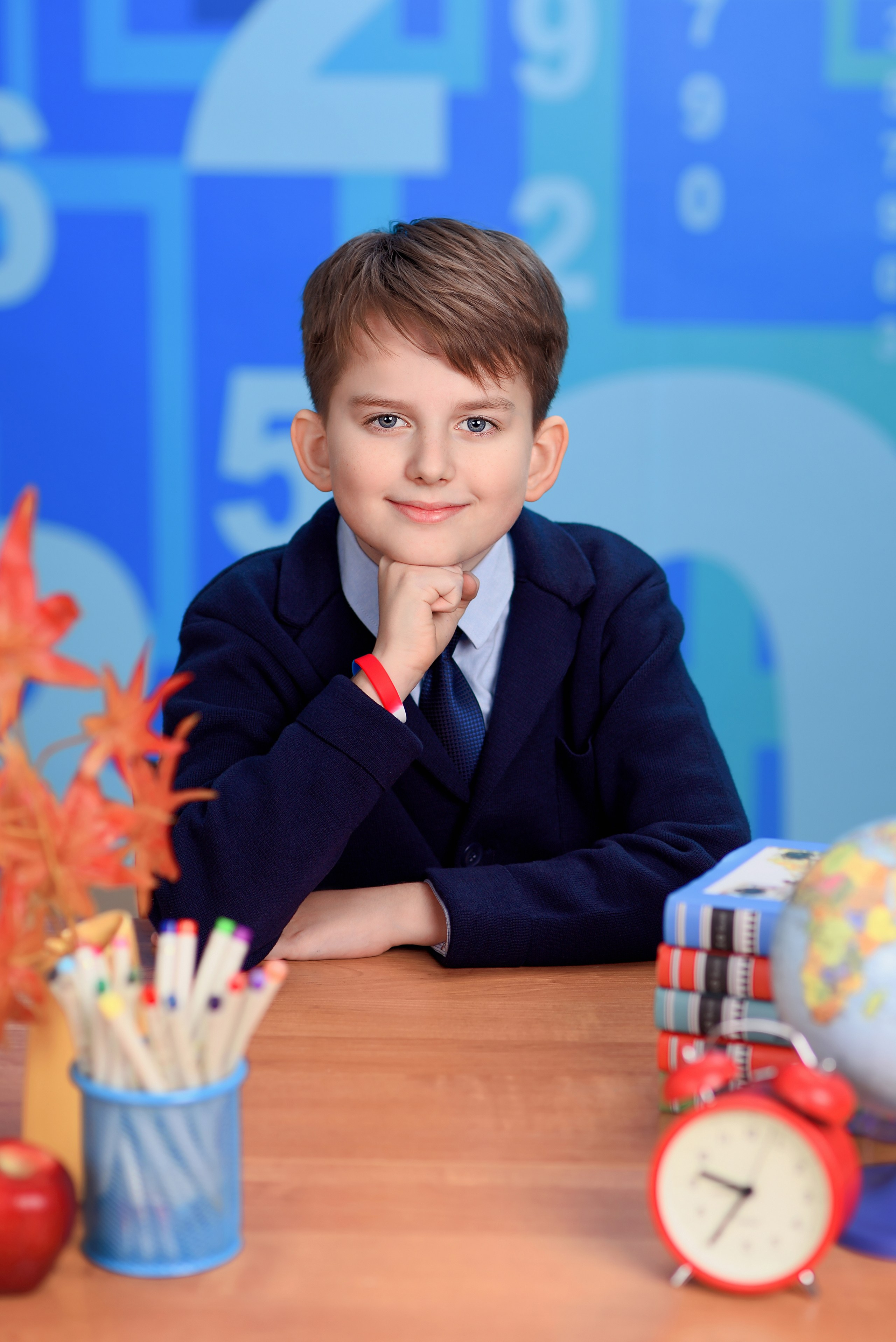 Классический портрет школьника за школьной партой с кулачком под подбородком.