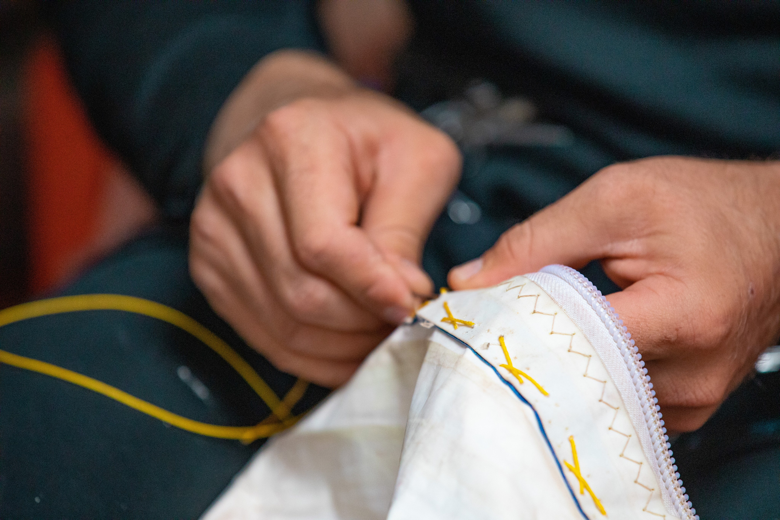 Яхтсмен латает парус. Руки крупным планом.