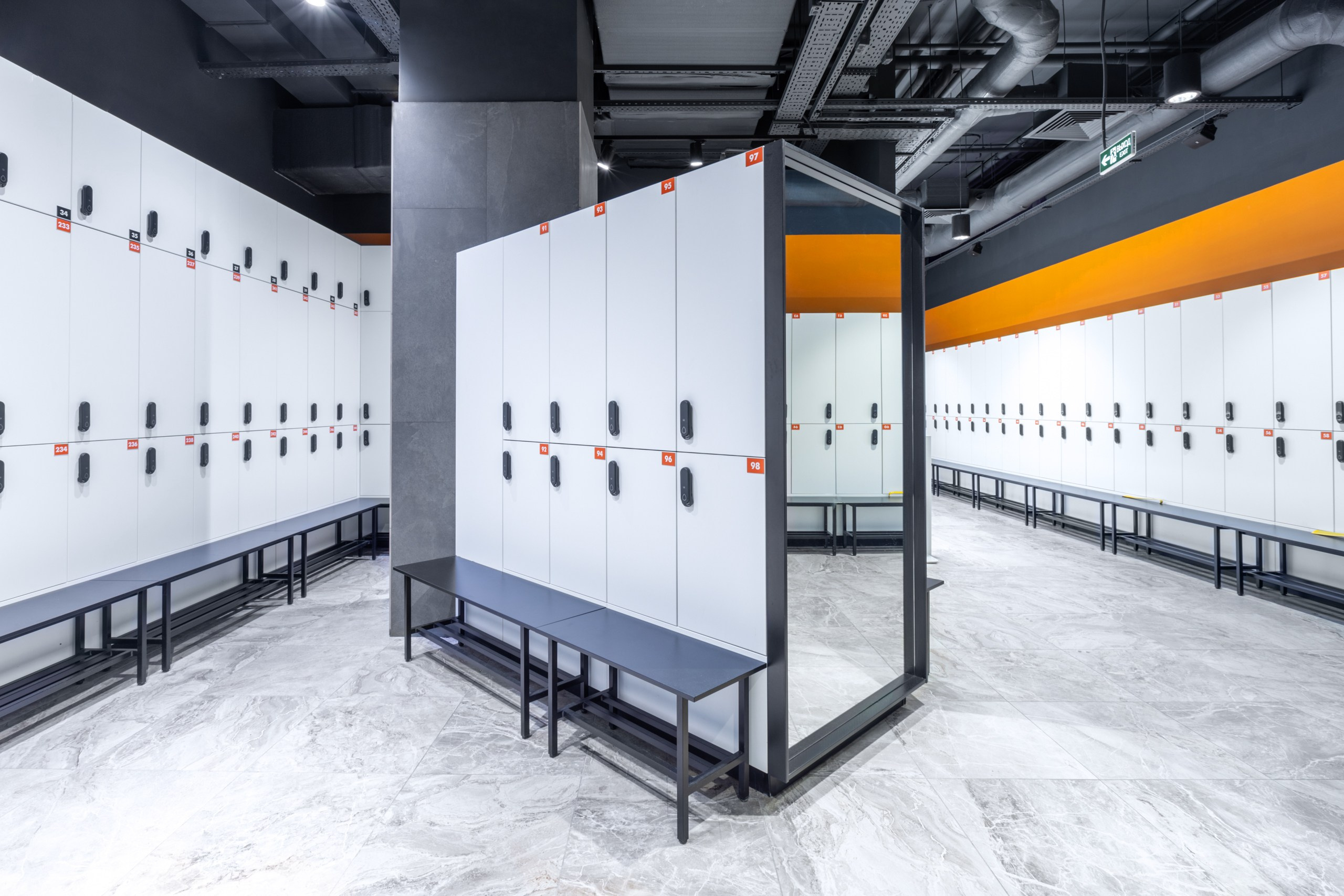 Стильная раздевалка в фитнес клубе. Белые с оранжевым шкафчики с зеркалами в тренажёрном зале. Стильный и дорогой дизайн фитнес центра.
