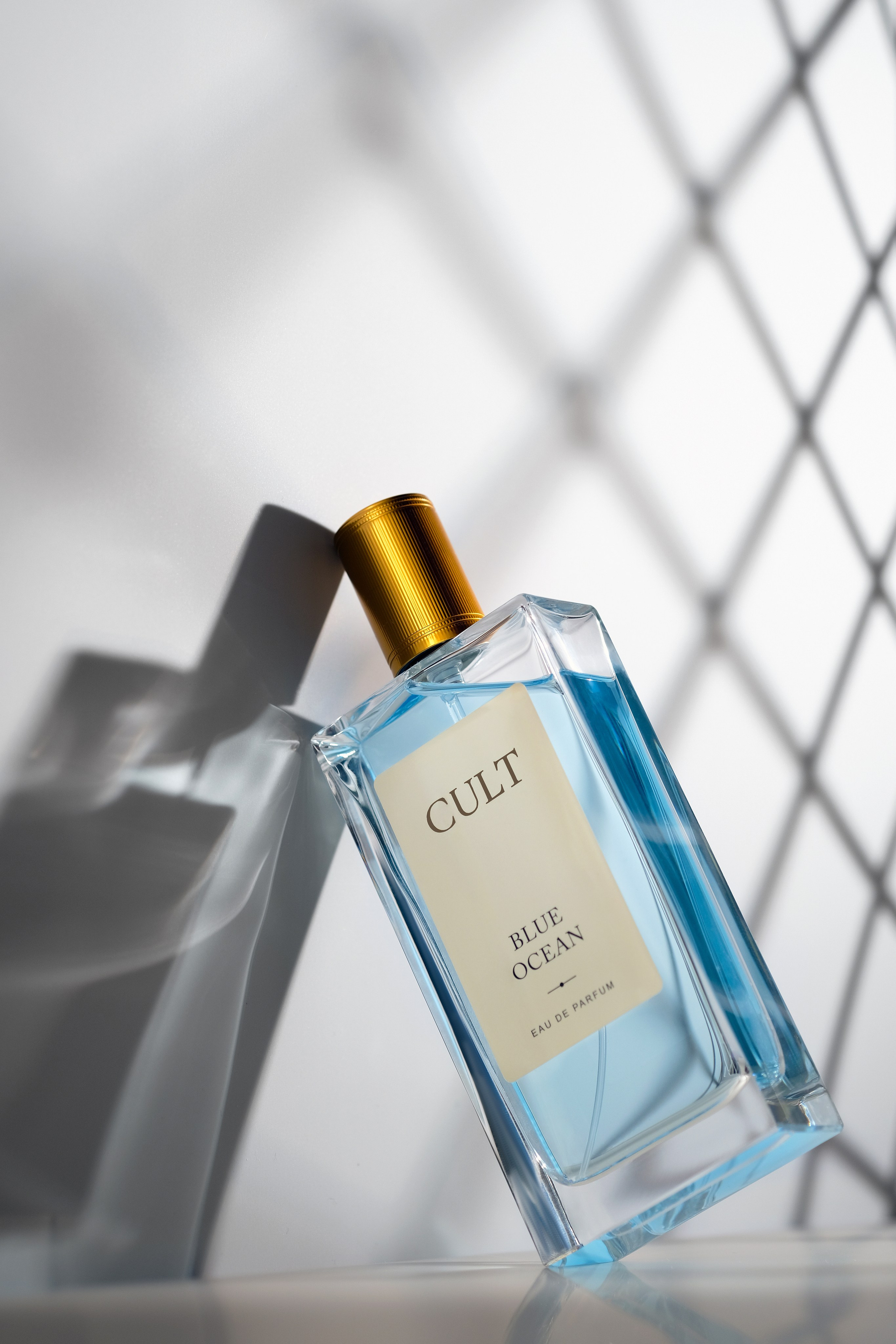 На переднем плане флакон женских духов с красивым свето-теневым рисунком