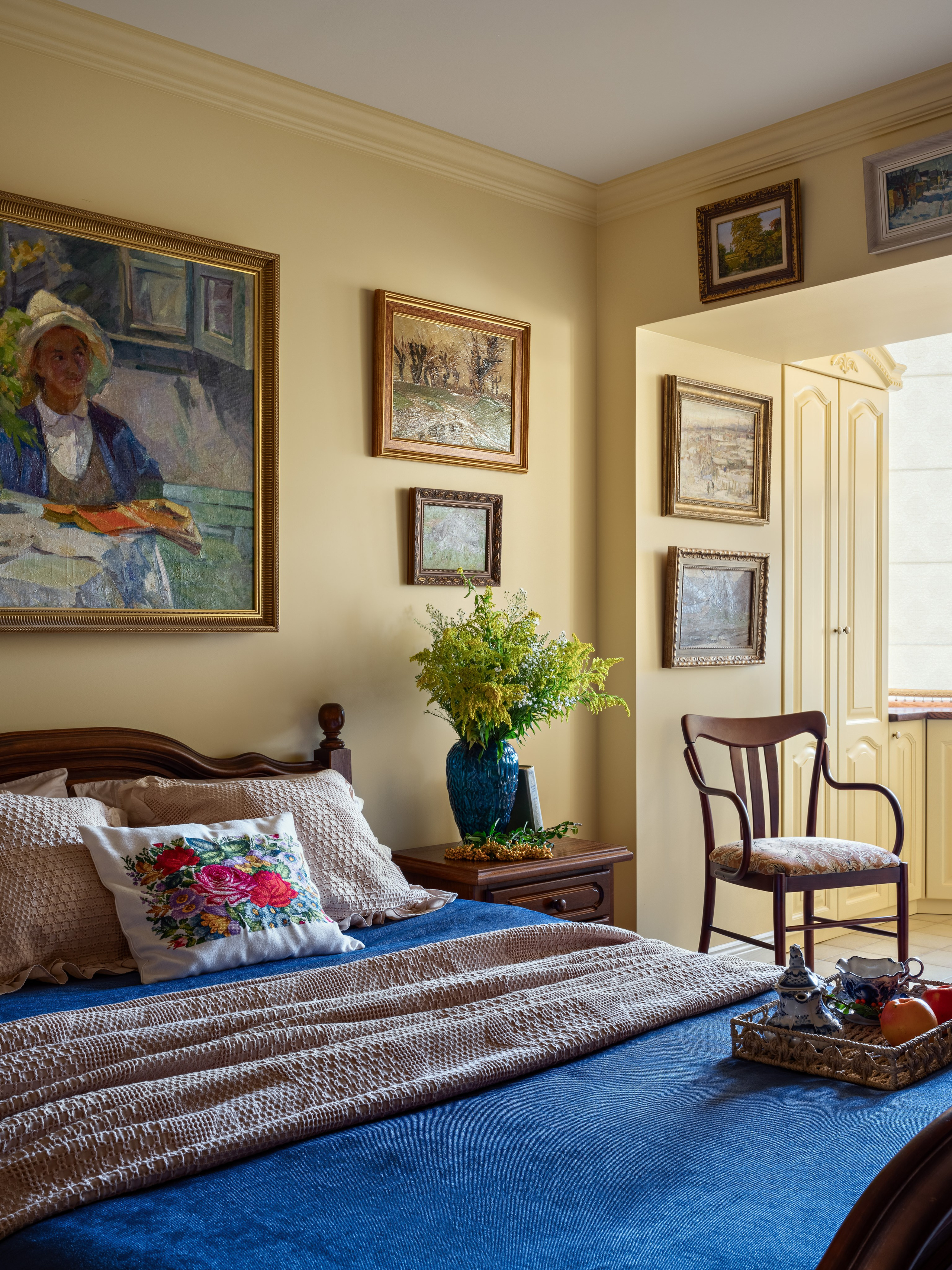 Фото стильного и уютного интерьера спальни с деревянной мебелью, картинами и декоративными акцентами, созданного в современном дизайне; проект Юлии Капункиной и Альбины Терещенко, стилистика Алины Нелень, фотограф Сергей Денисенко.