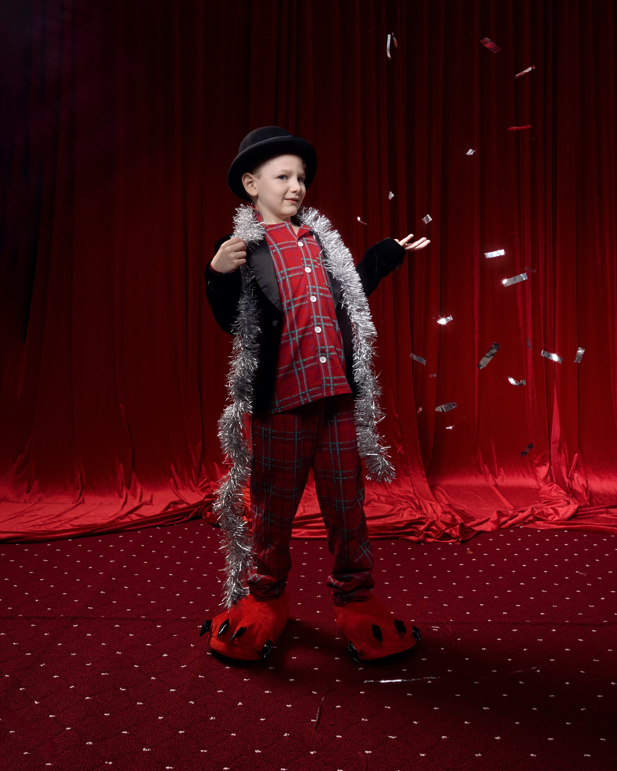 Забавная фотосессия для детей: мальчик в пижаме и шляпе позирует на сцене с конфетти. Семейный фотограф создает яркие и незабываемые воспоминания для семьи. Новогодняя фотосессия в фотостудии