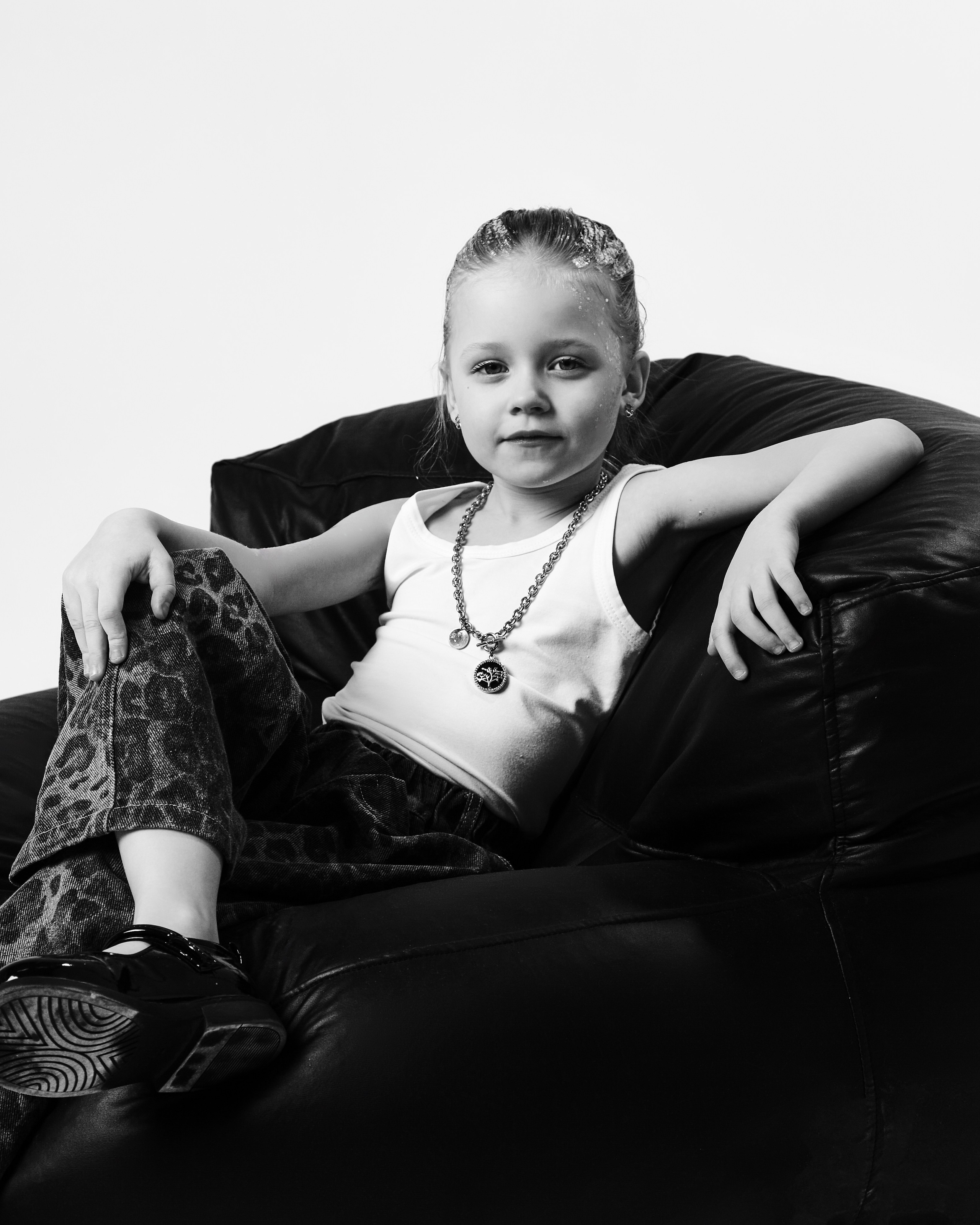 Чёрно-белый студийный портрет девочки в майке на пуфике иваново