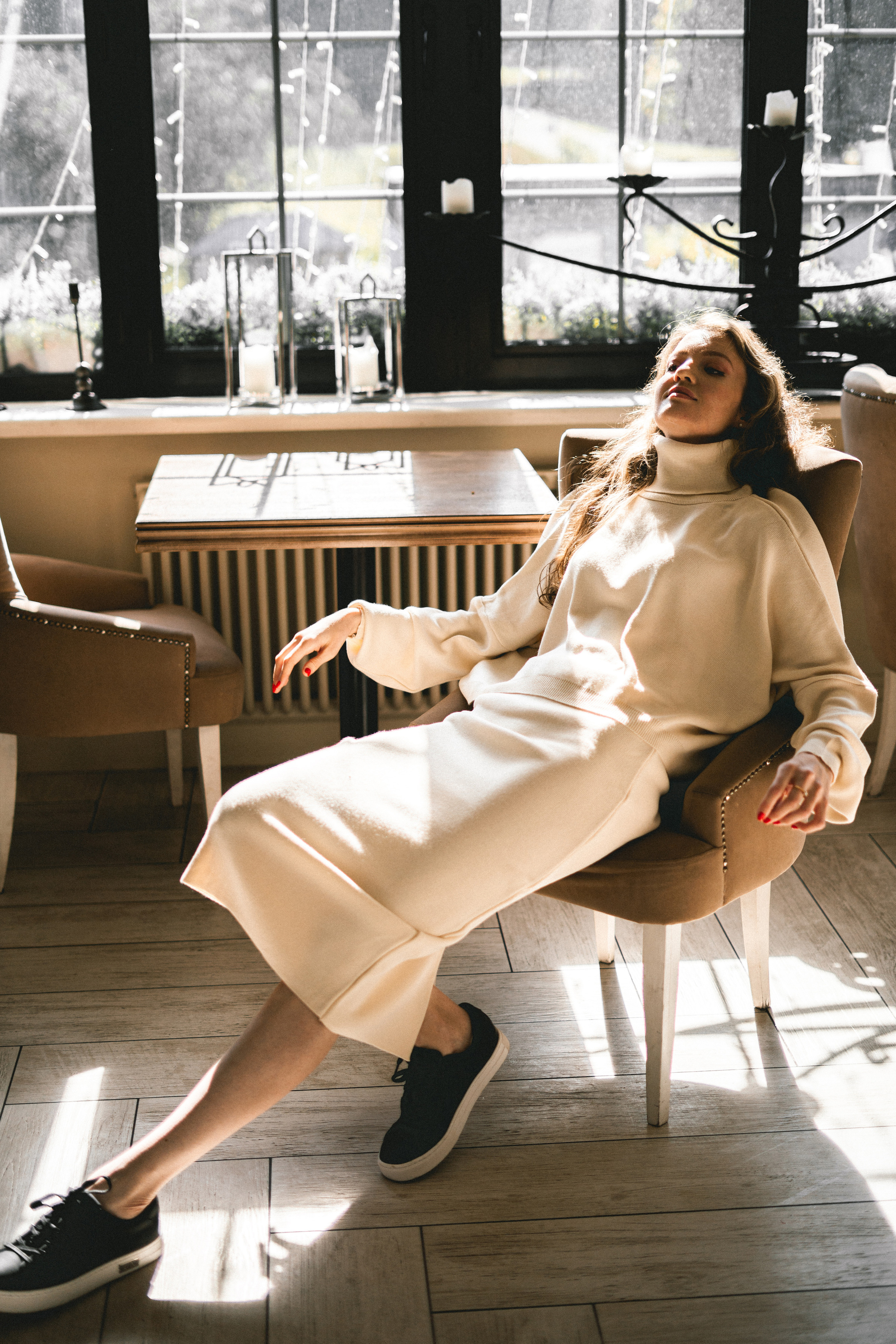 a girl in a white outfit in a cozy corner of the café