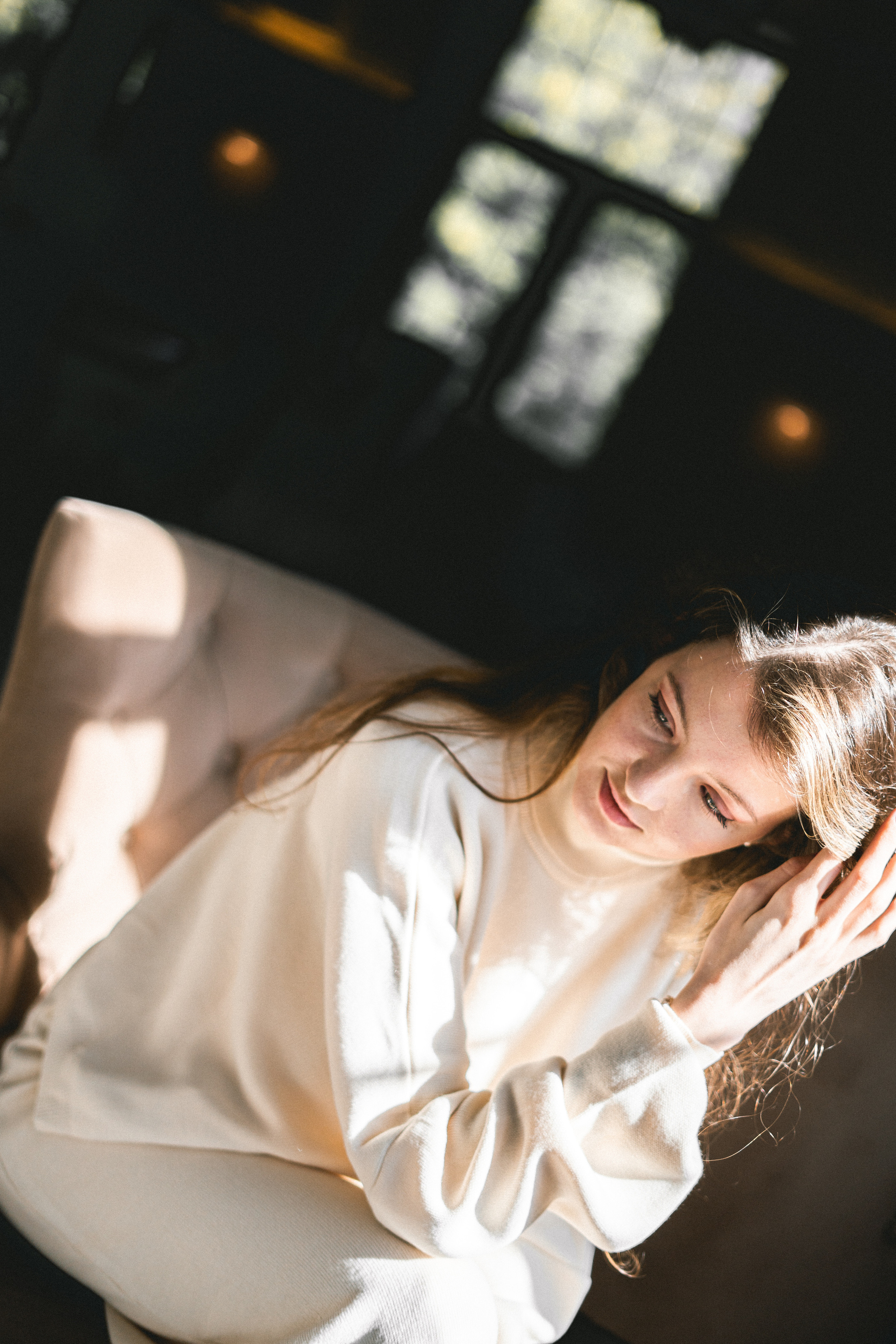 a girl in a white outfit by the window with a view of the street