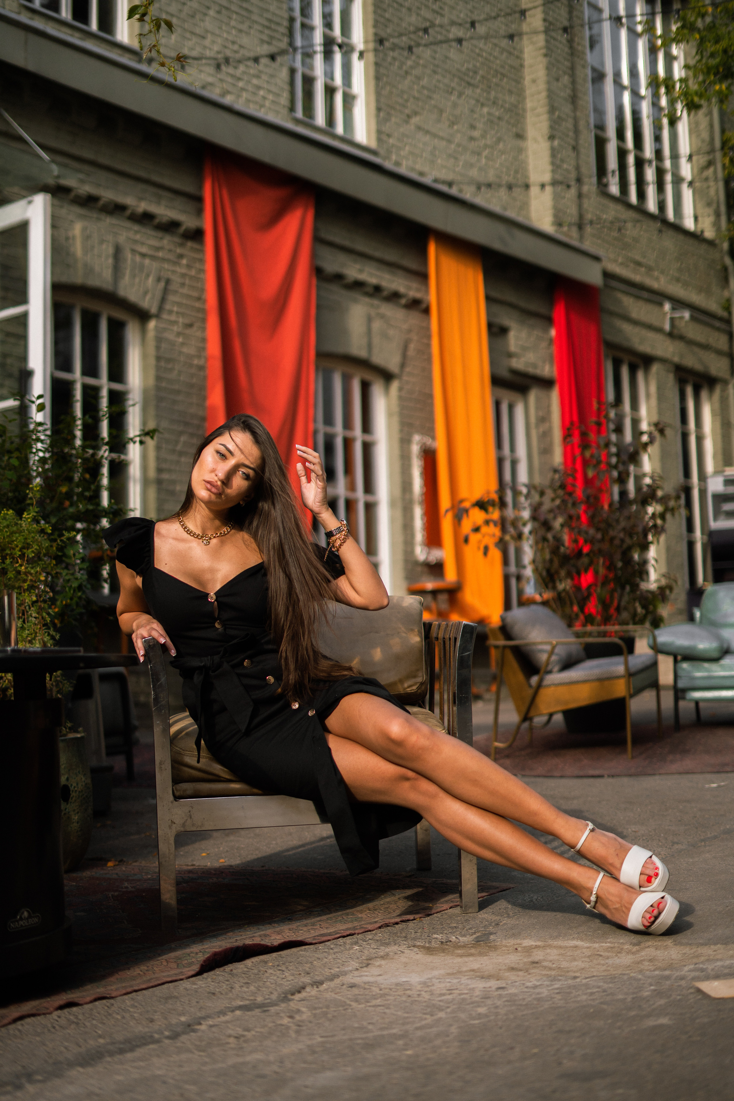 a girl in a black dress sitting on the steps in a cozy courtyard