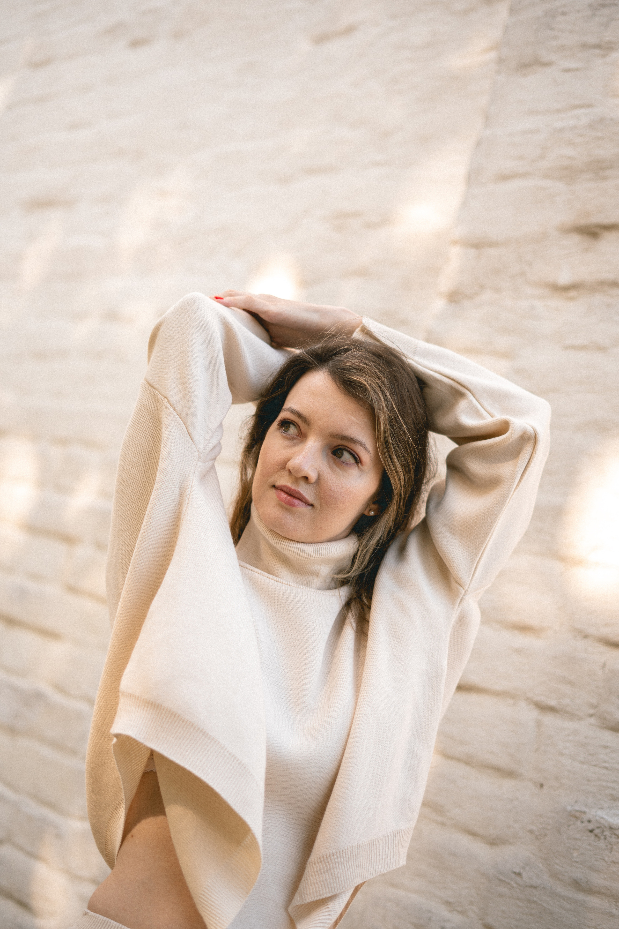 in a white outfit against a white wall