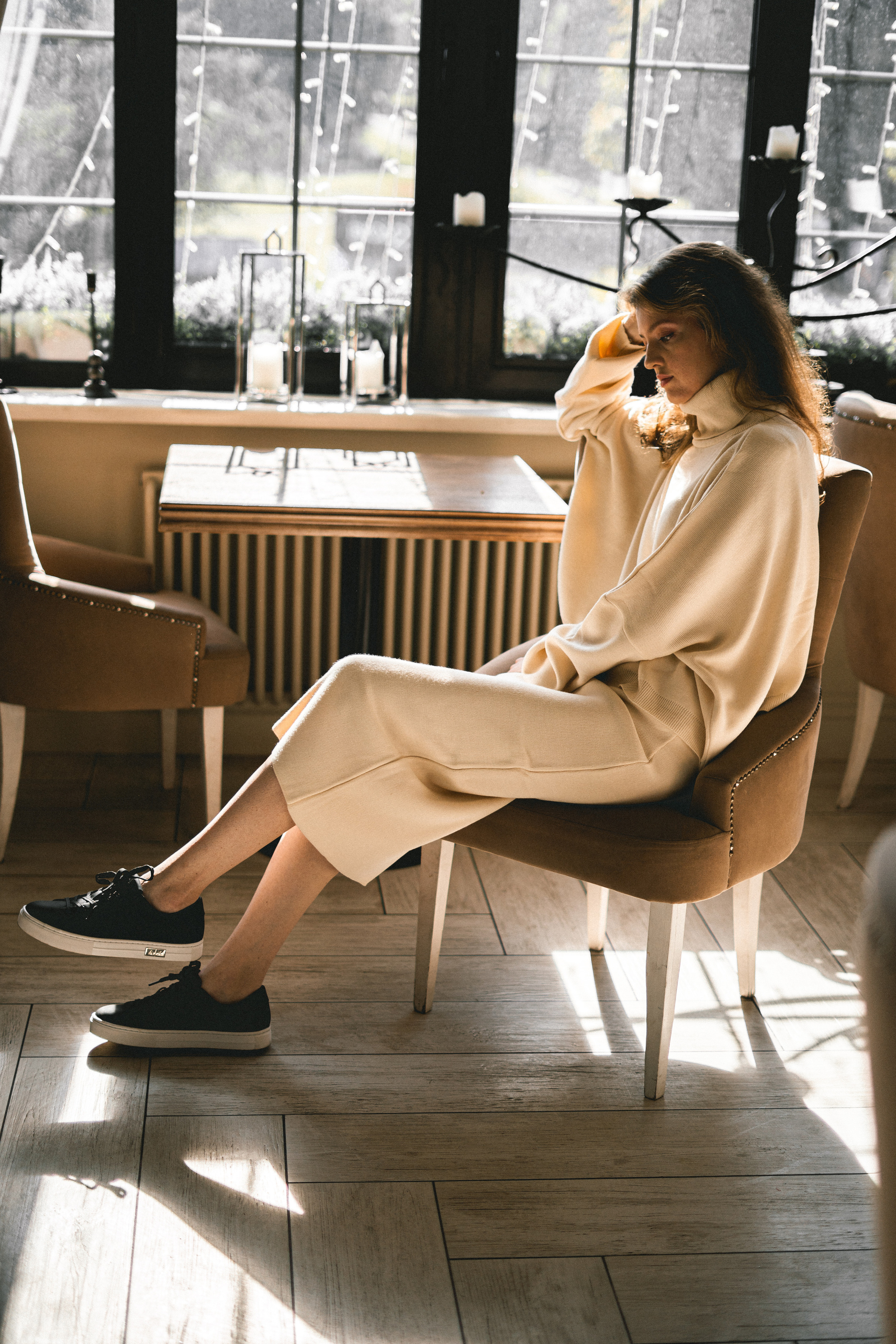 a beautiful girl in a white outfit posing among floral arrangements in the café