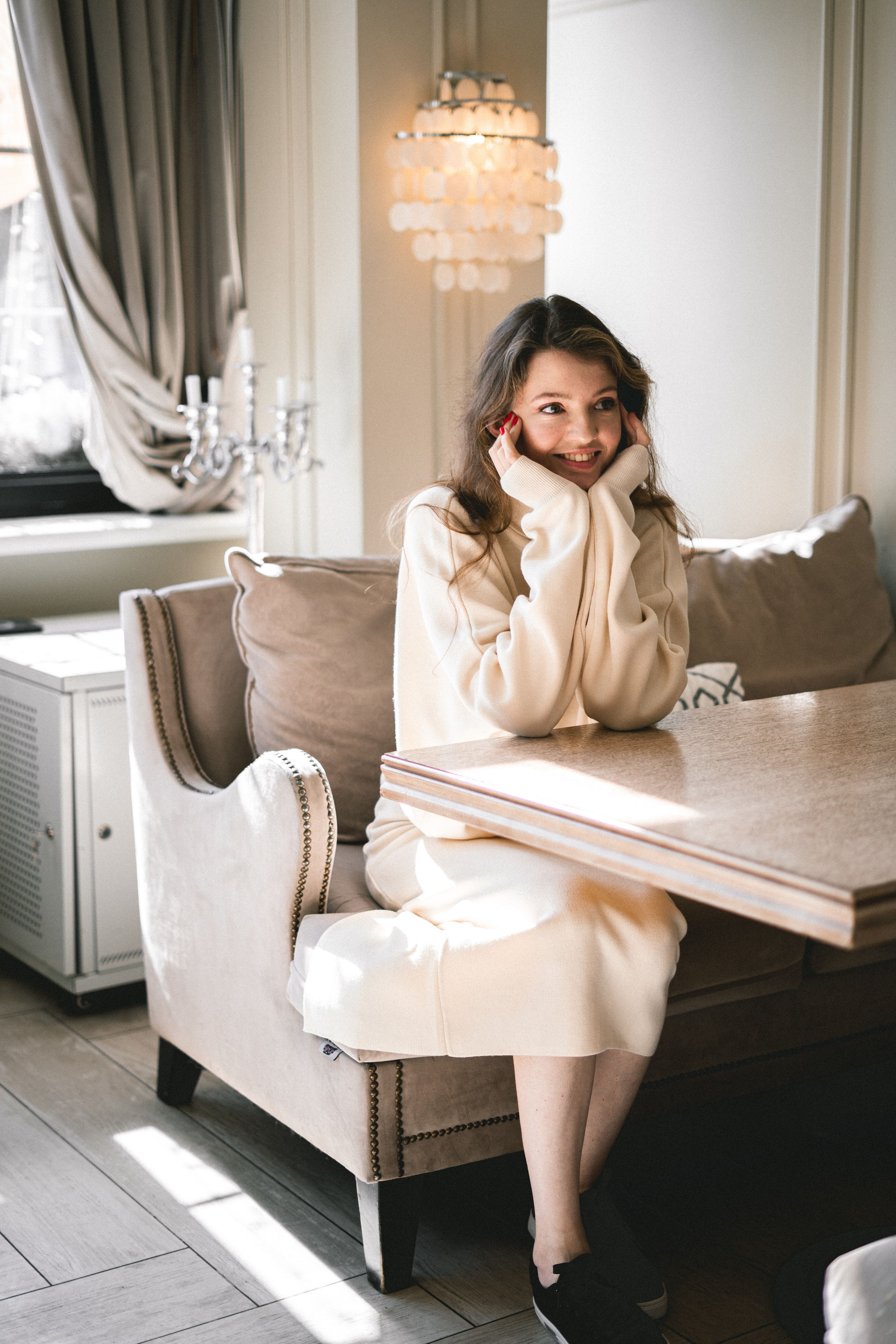 a beautiful girl in a white outfit posing with a smile against the café décor