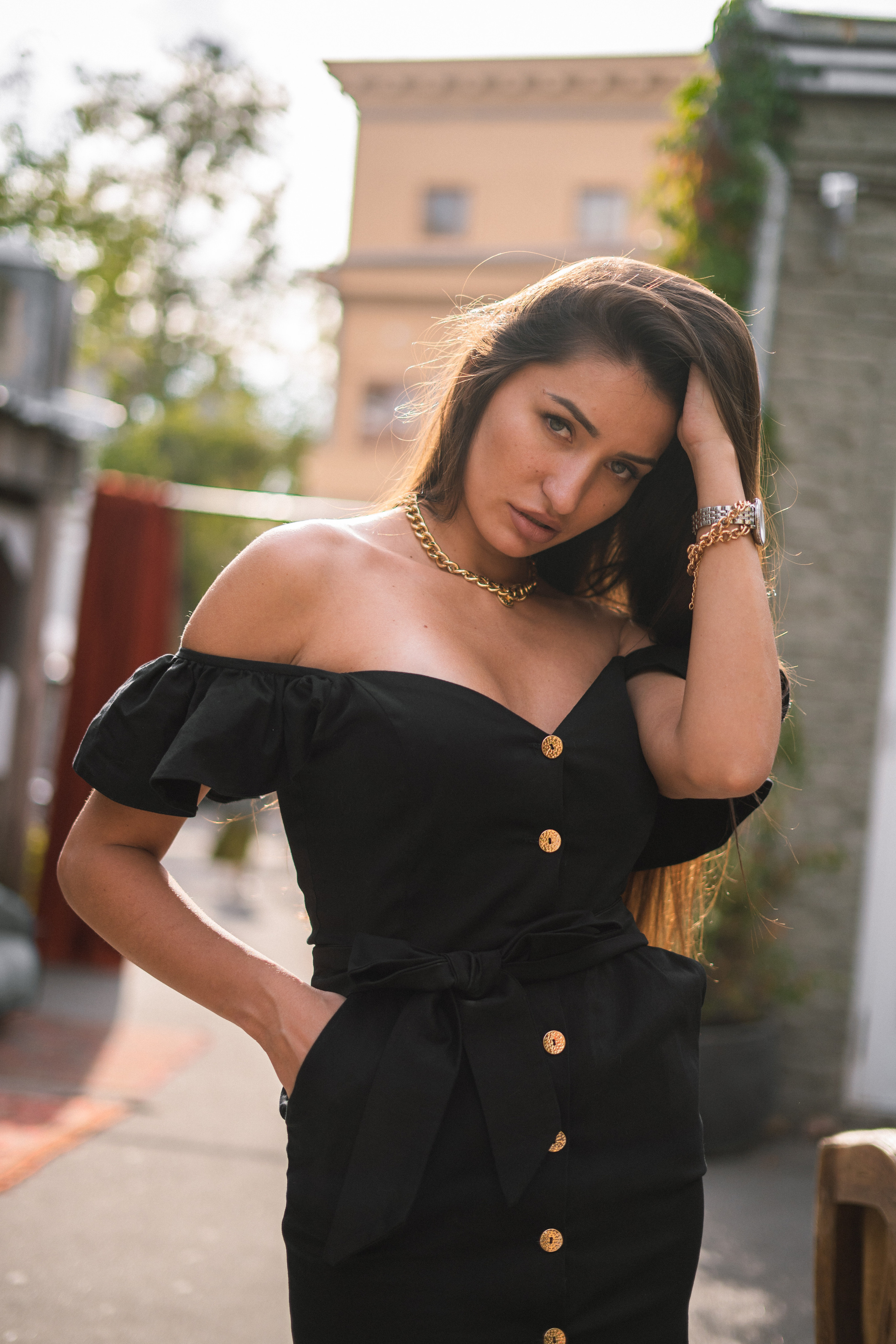 a beautiful girl in a black dress in front of a cozy café in a courtyard