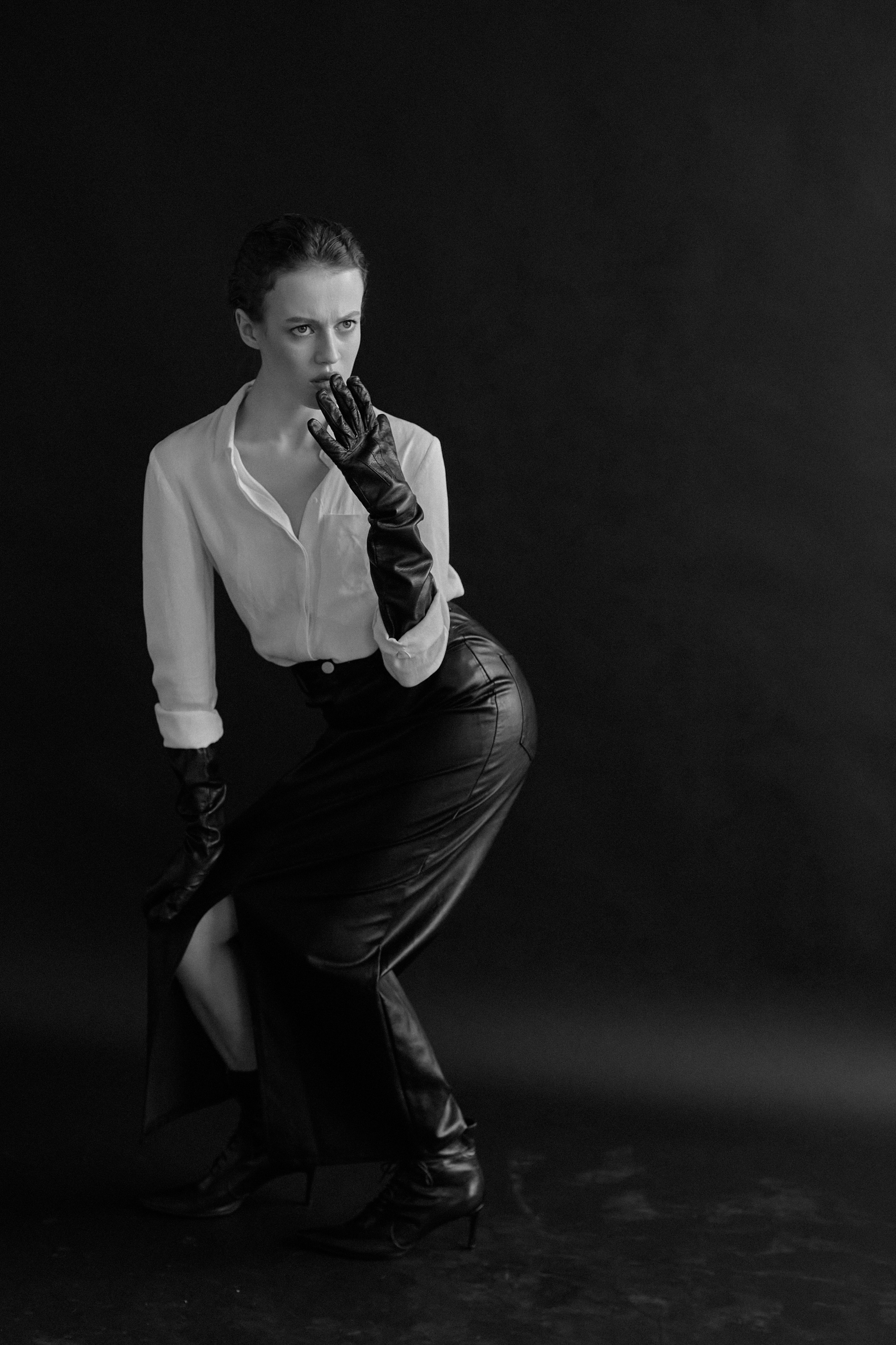 Фотограф в Москве. Студия. Студийный портрет. Девушка в черных кожаных перчатках и строгом костюме на черном фоне. Женский портрет. Воркшоп. Черно-белое фото.