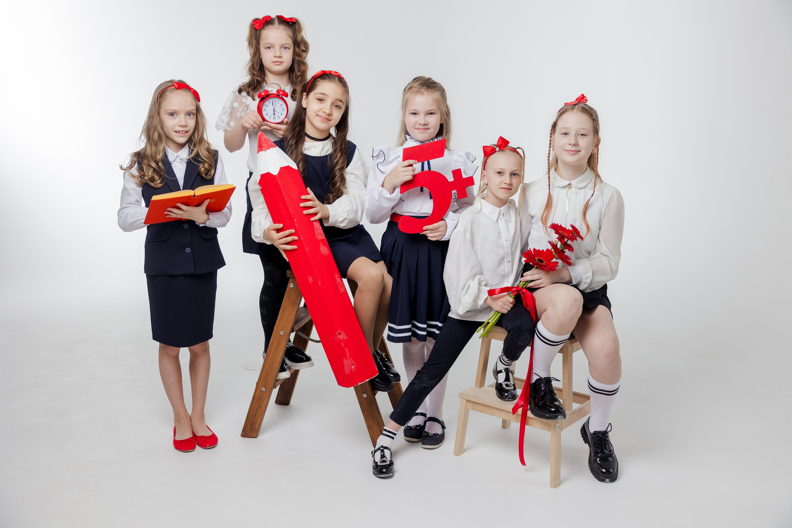 Девочки стоят вместе в студи в одежде с красными акцентами с красным карандашом