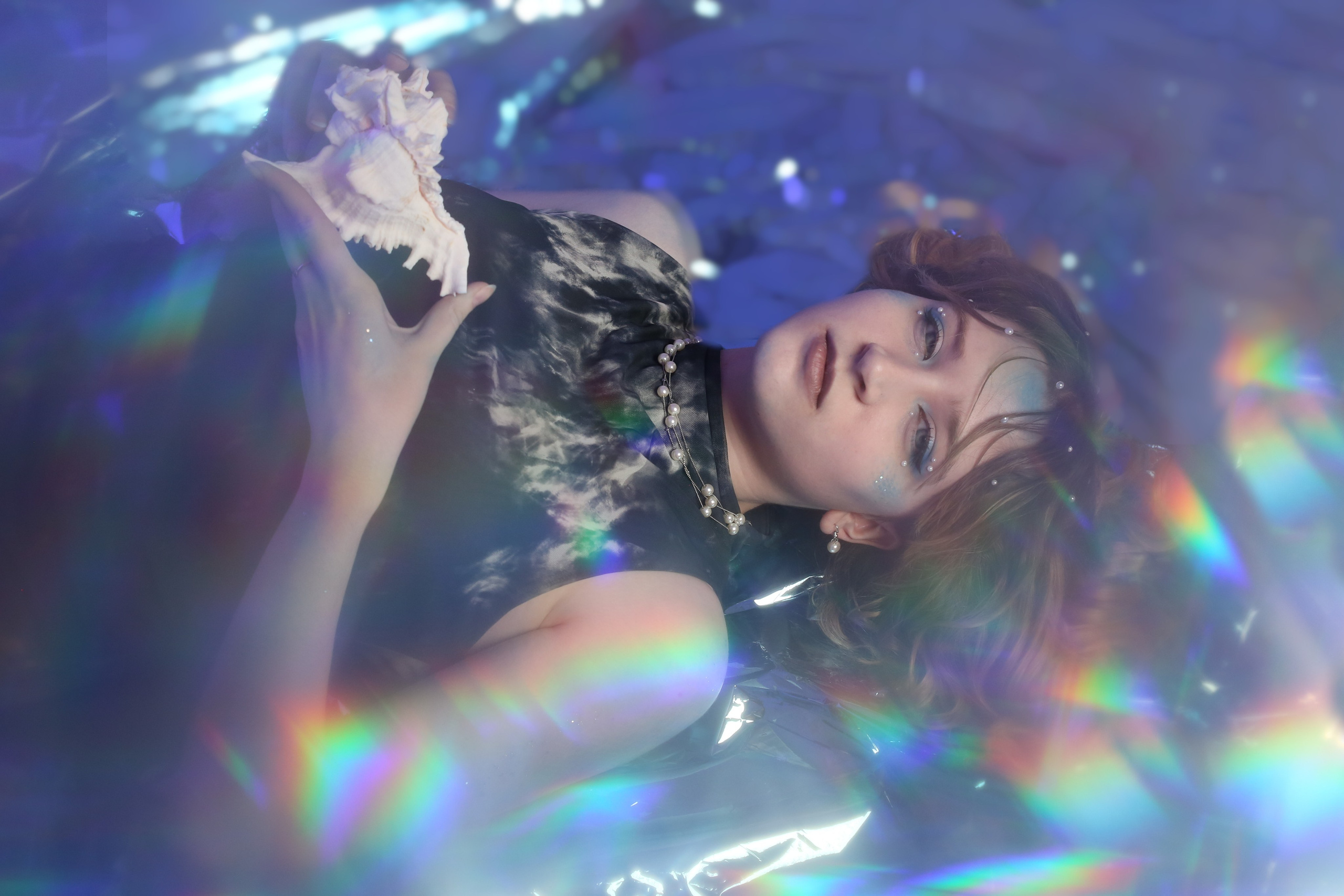 Творческая фотосессия «Ундина»: девушка в черном платье лежит в воде и смотрит в камеру