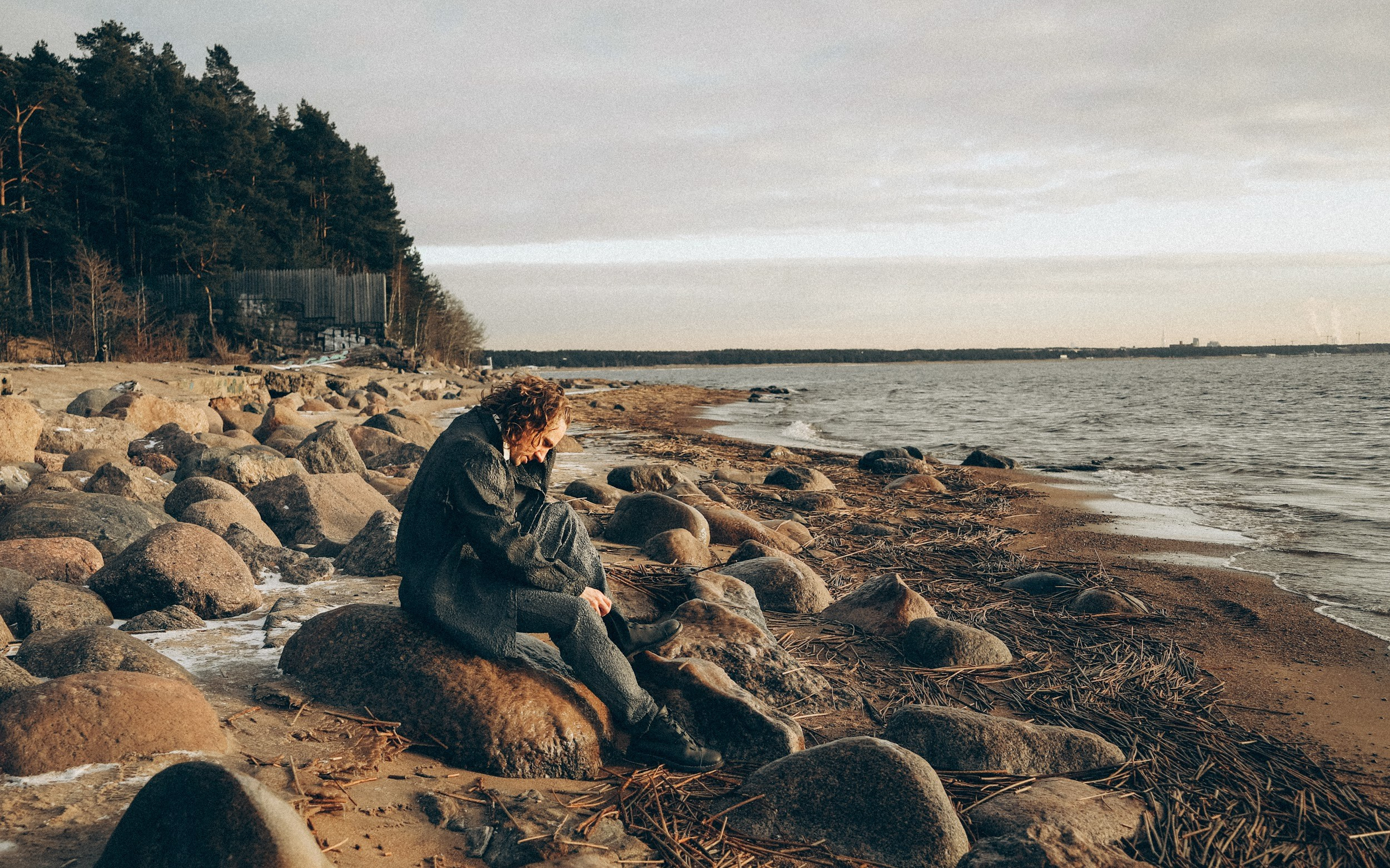 мужчина на фоне волн и оранжевого неба Финского залива.