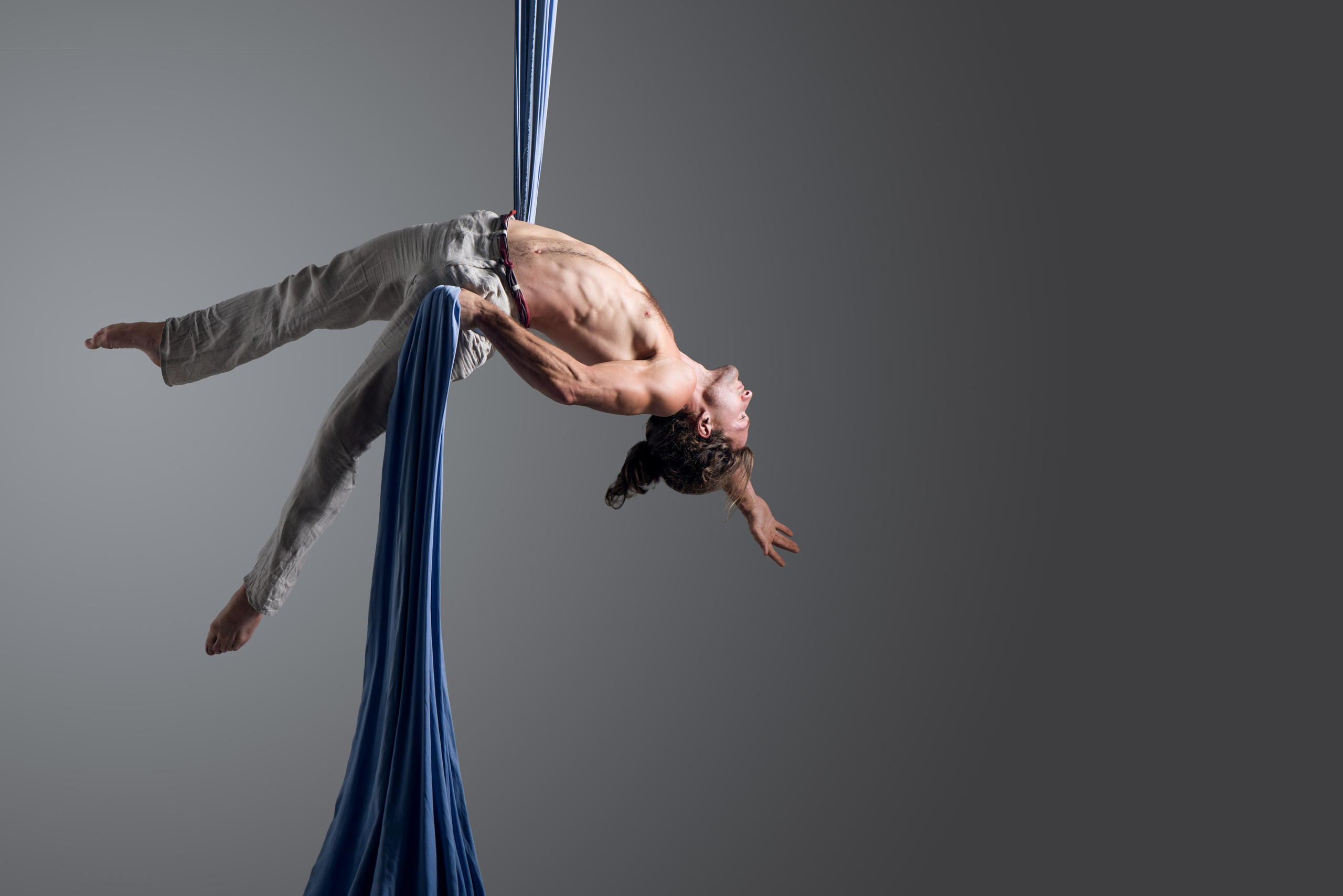 Художественная портретно-спортивная фотосъёмка мужчины-акробата на воздушных полотнах. Динамичная поза, драматичное световое решение. Контент для артистов, шоу-программ и спортивного портфолио