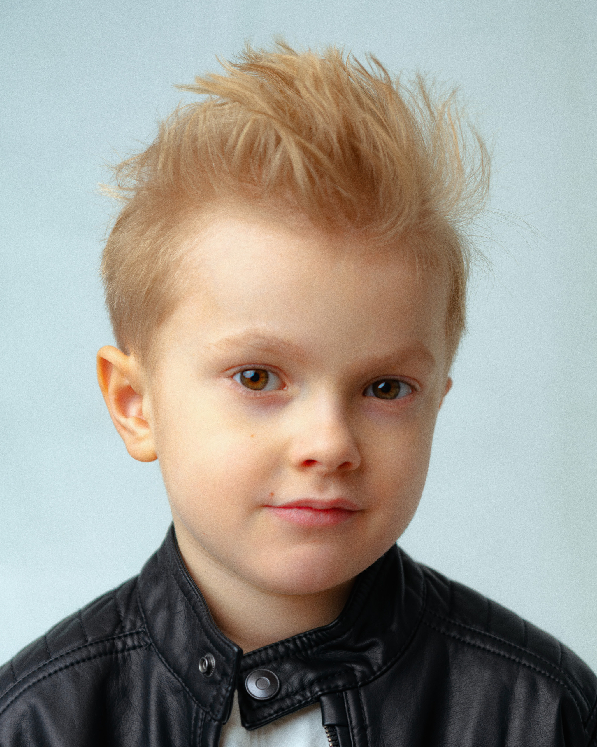 Крупный портрет мальчика в кожаной куртке и ирокезом на голове