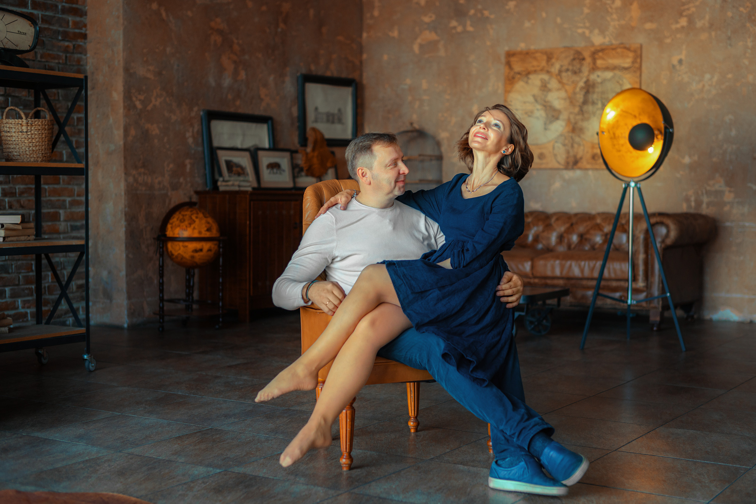 Девушка сидит на коленках мужчины сидящего в кресле посреди комнаты