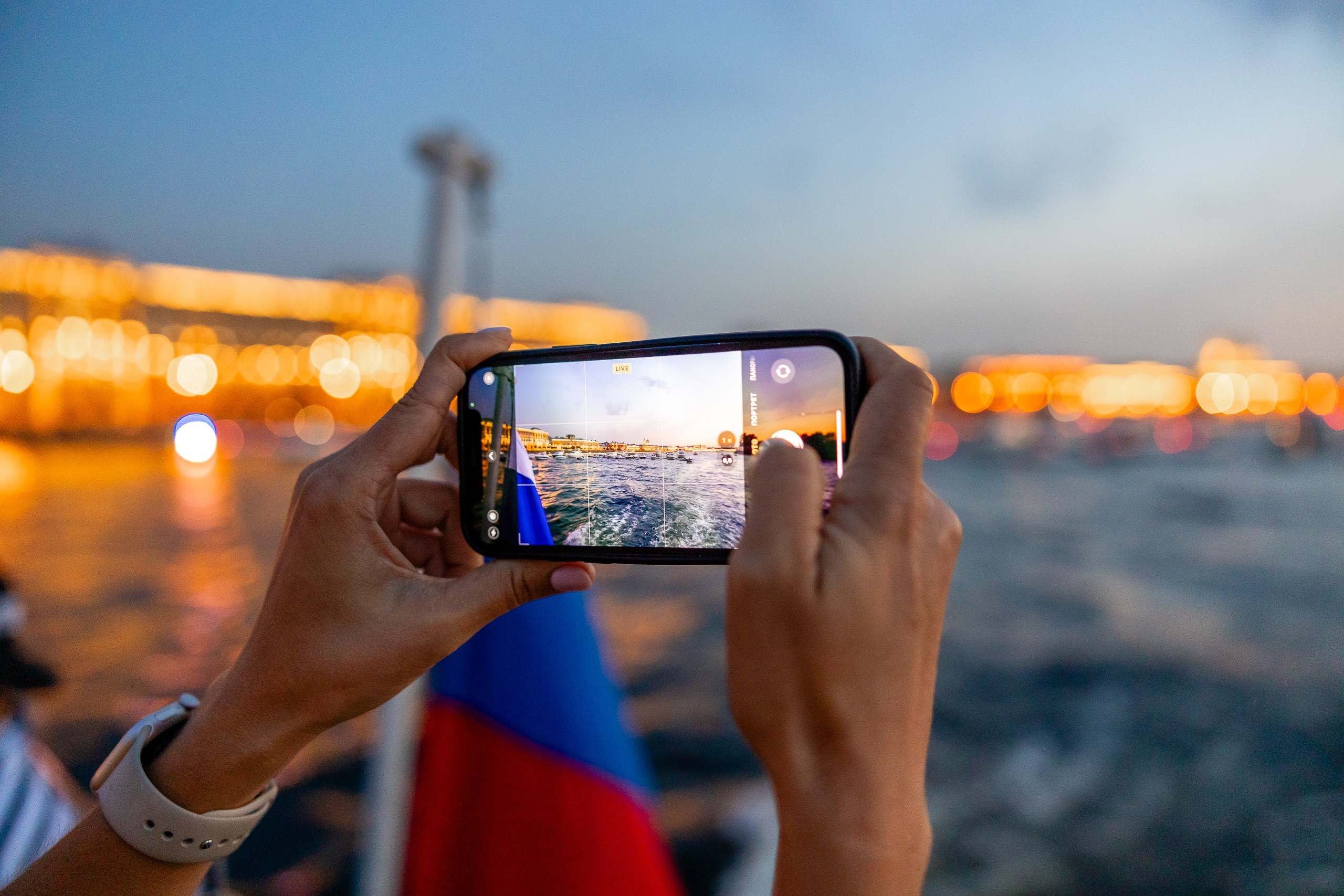 Вечерний вид Питера с борта теплохода на телефоне в руках туриста