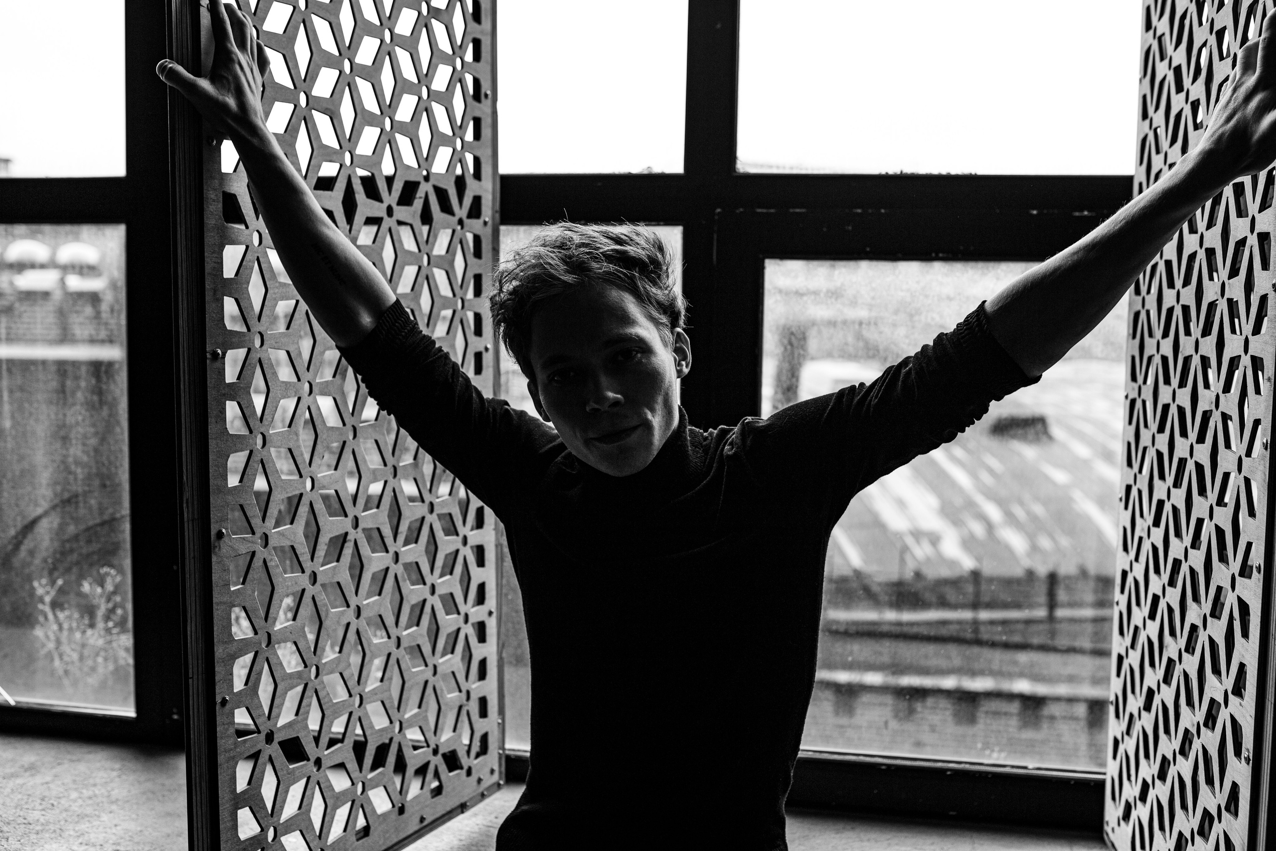 Черно-белая фотография парня у окна.