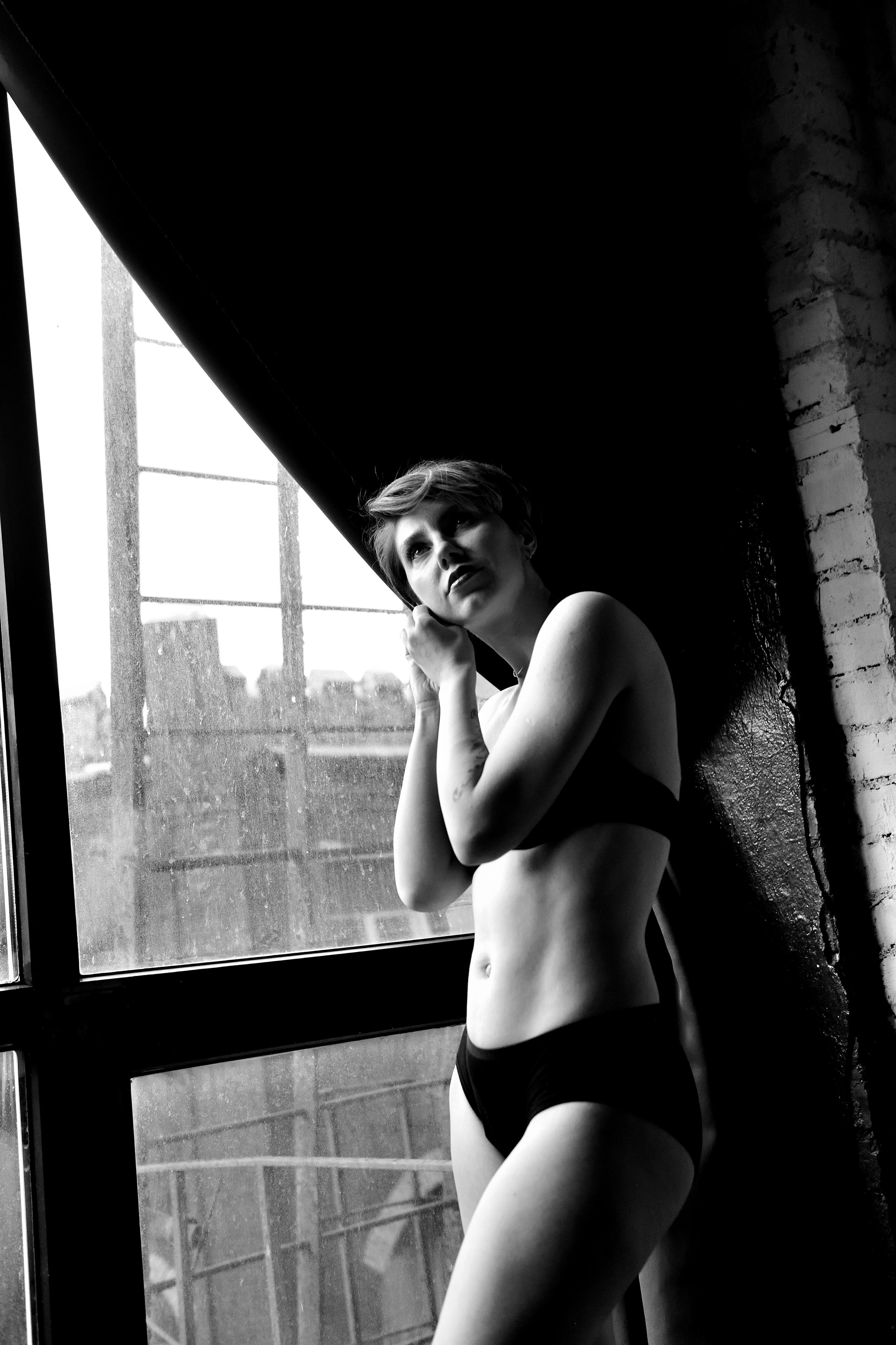 Девушка в красивом нижнем белье стоит у окна.