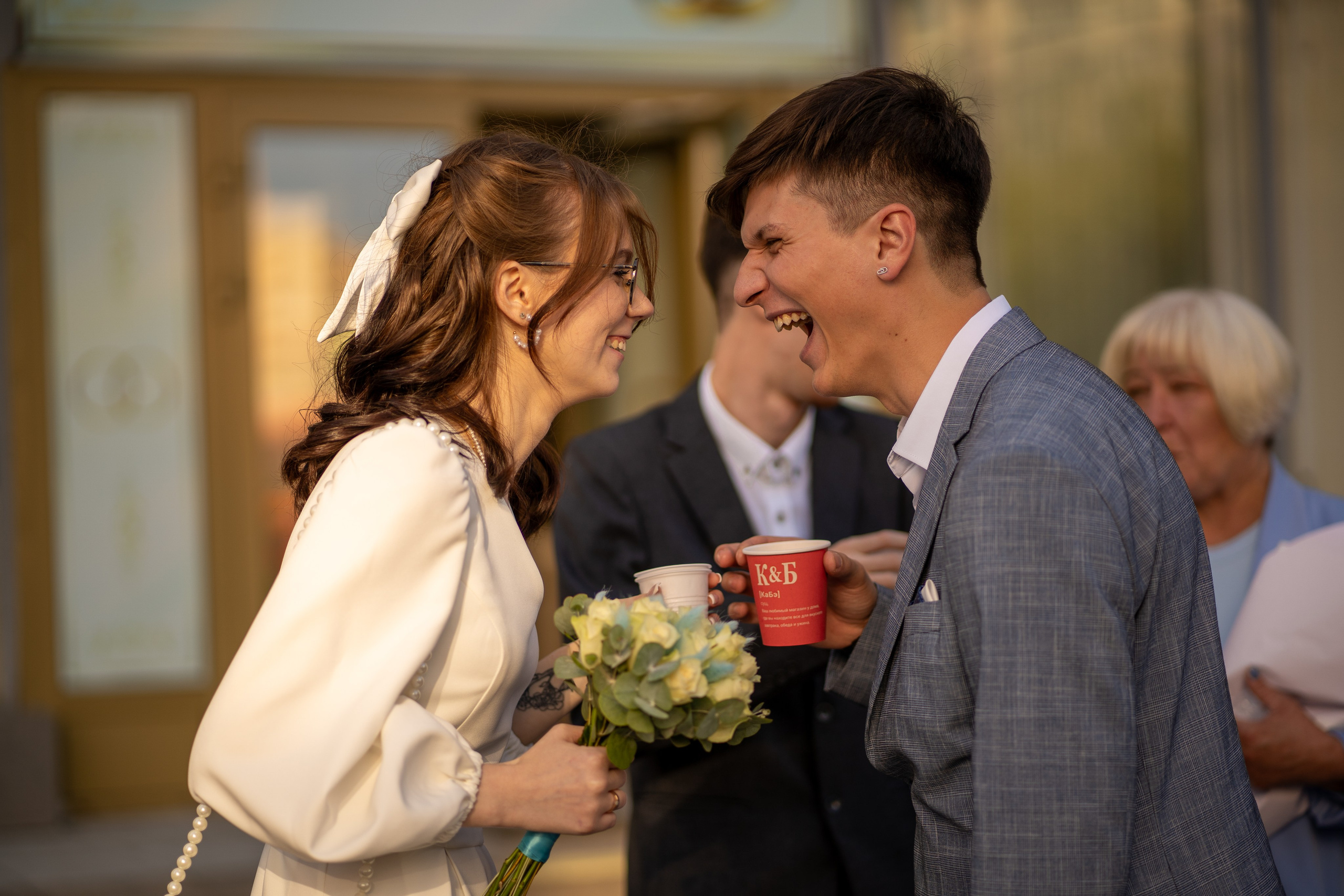 Жених и невеста смеются у загса после росписи