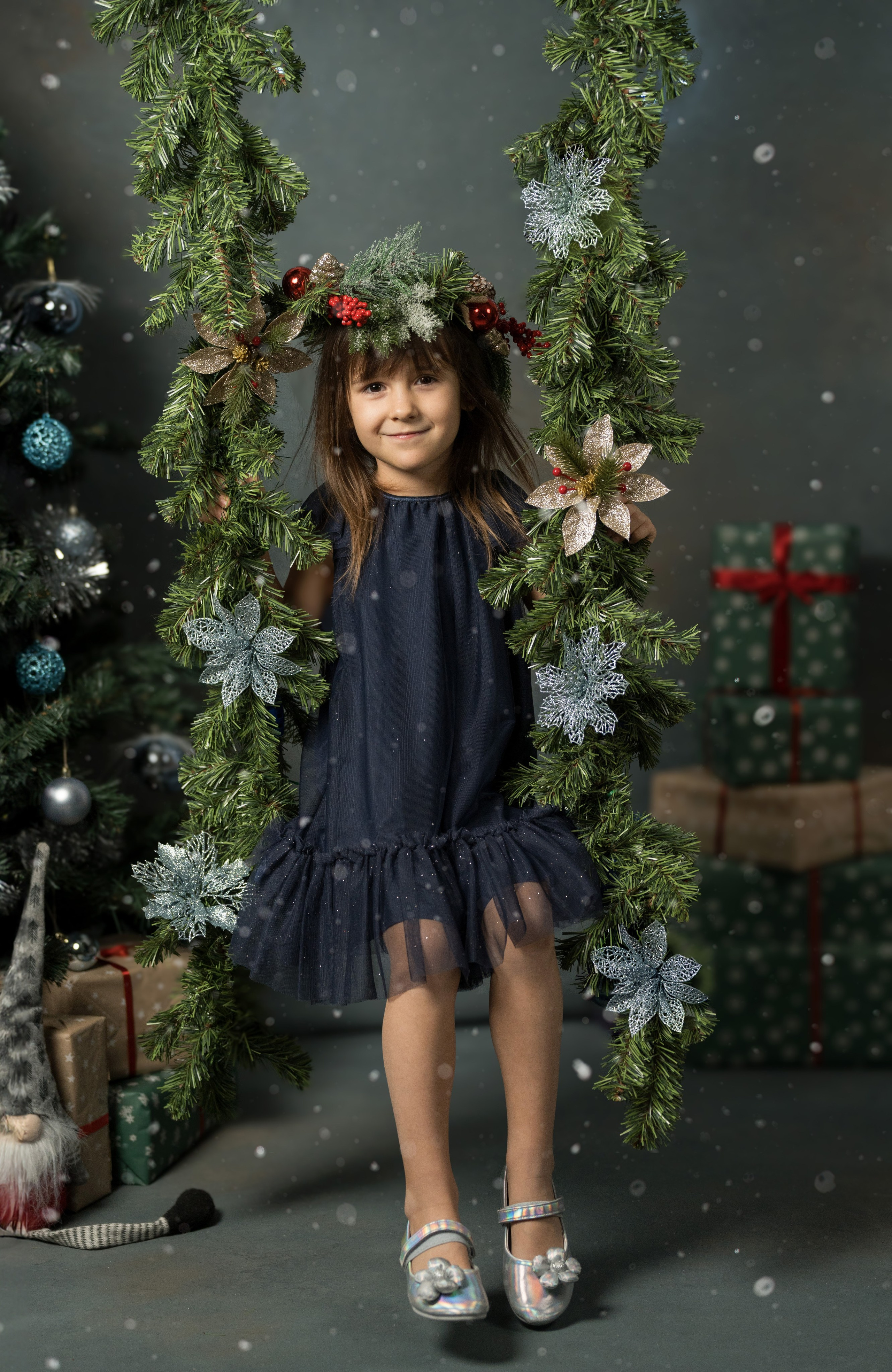 Девочка качается на новогодней качели счастья.