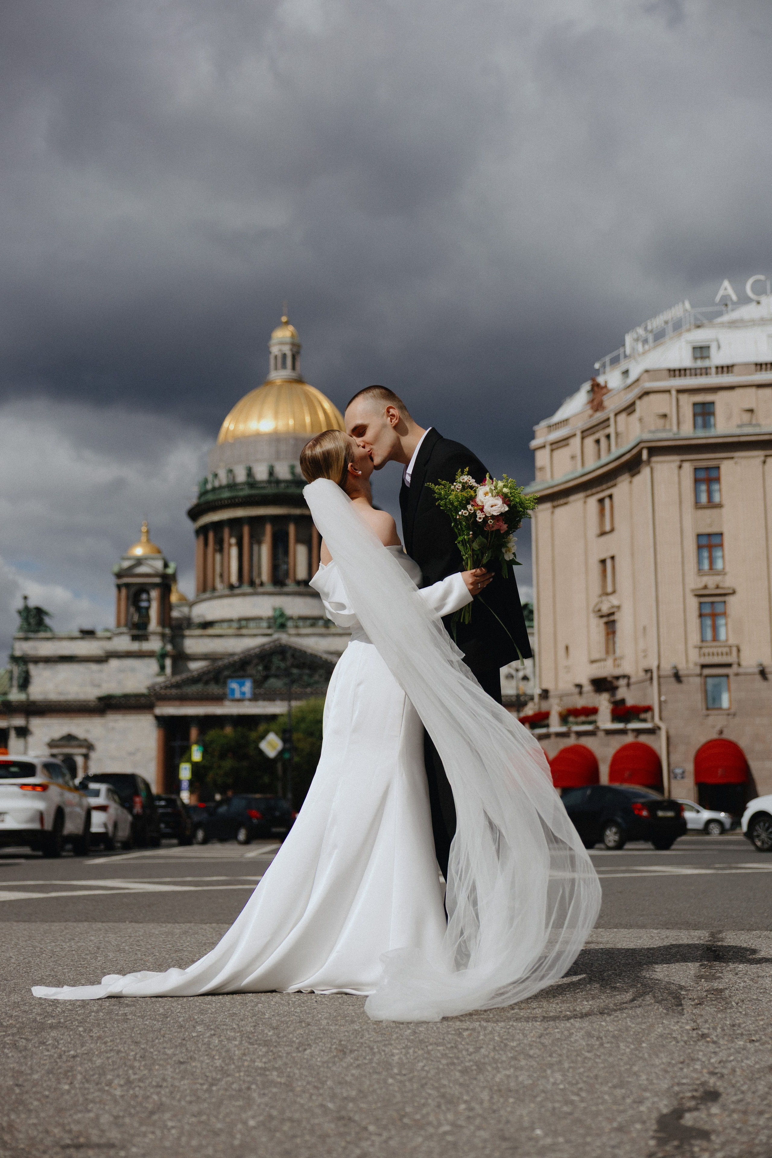 Свадебная фотосессия на фоне Исаакиевского собора в Санкт-Петербурге: жених и невеста целуются под фатой.