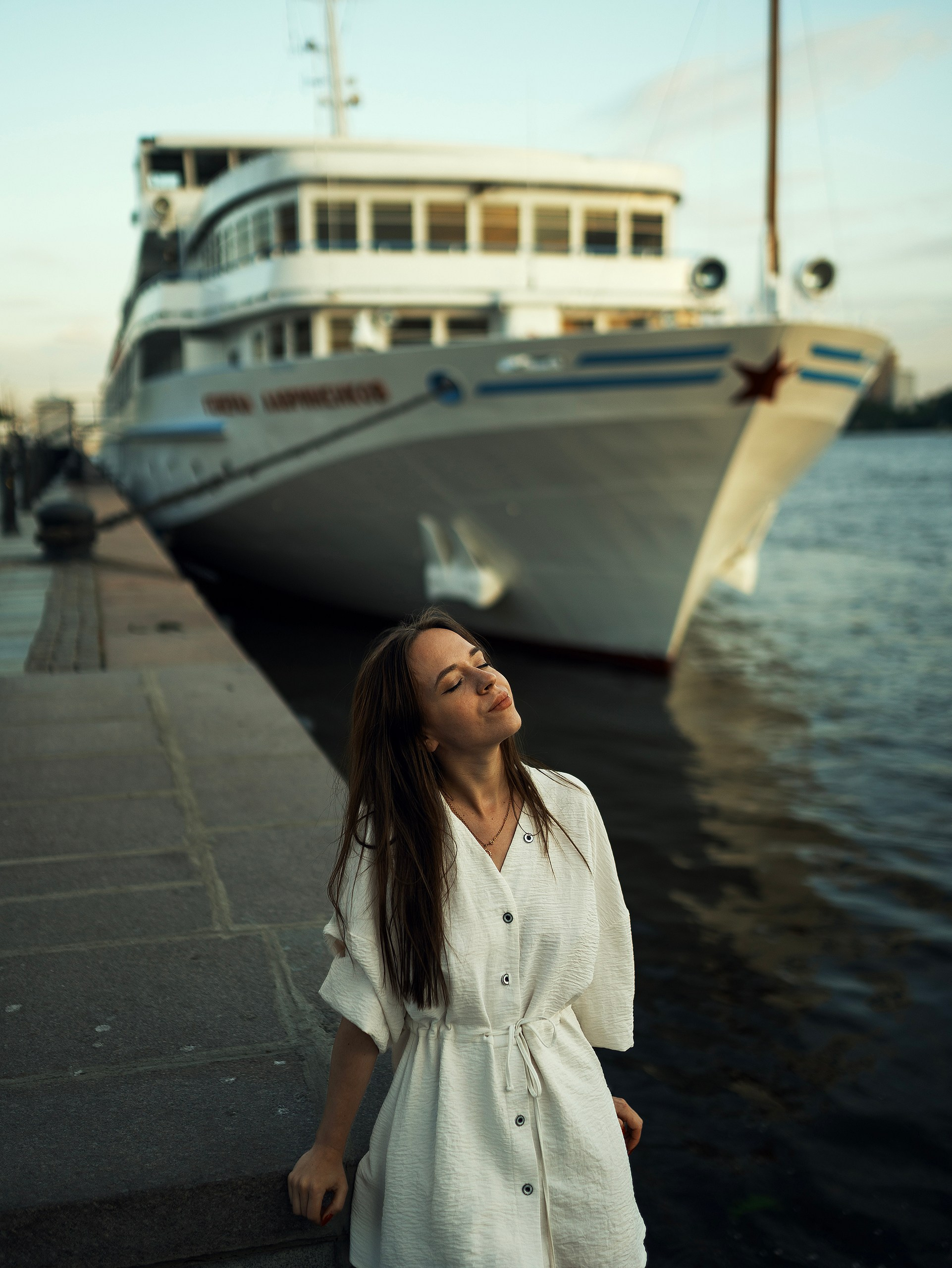 Девушка в закатном солнце на фоне кораблей