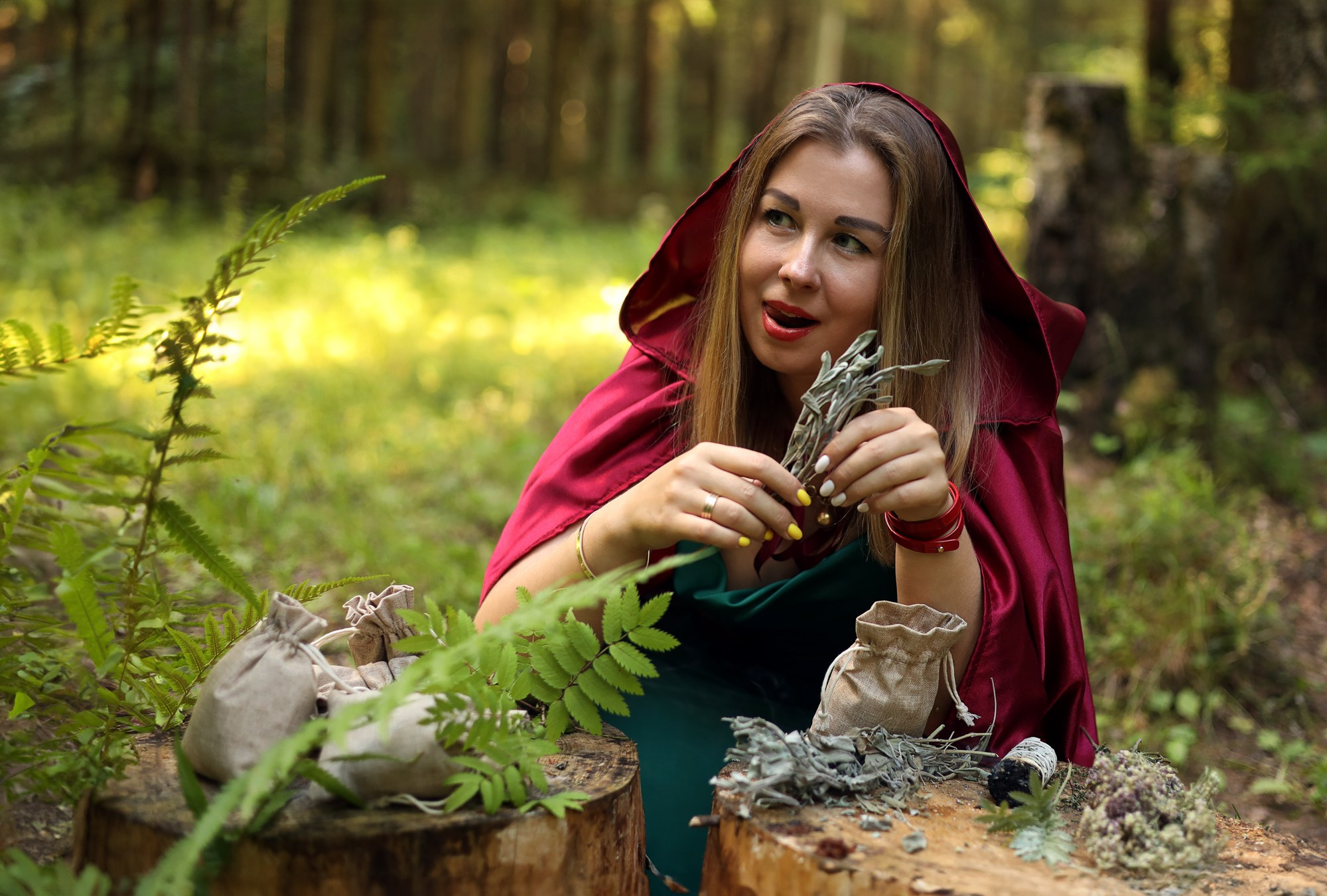 девушка сидит в лесу с мешочками разных трав на тематической фотосессии
