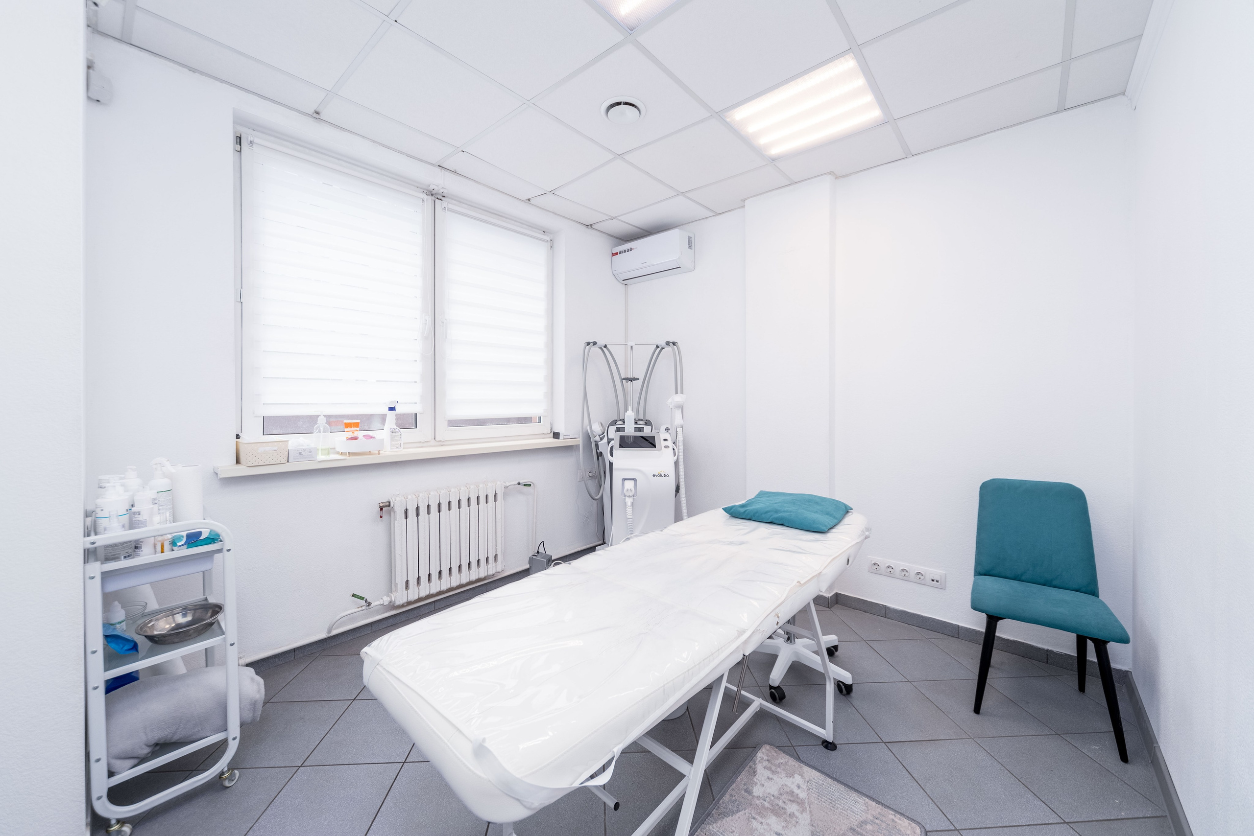 Интерьер косметического кабинета - кушетка, медицинское оборудование и большое окно