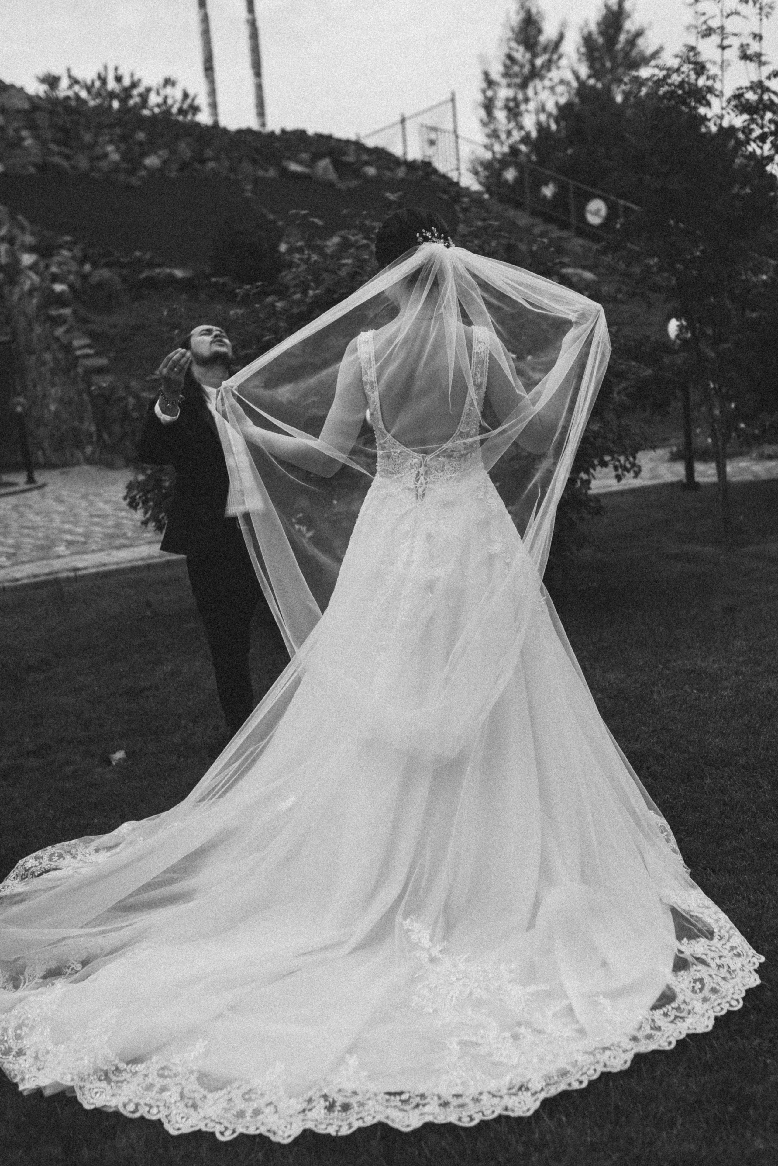 Эстетичный черно-белый кадр невесты со спины. Акцент на длинную фату и кружево платья.