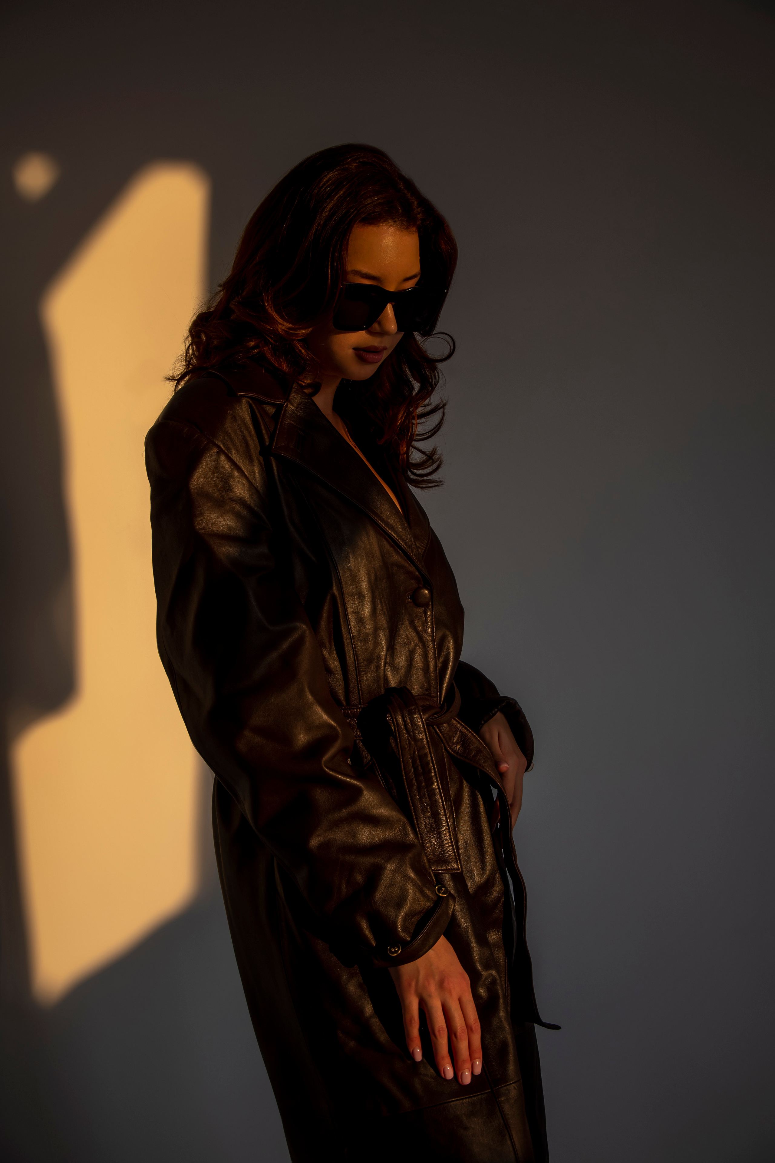 Красивая девушка в кожаном плаще на голое тело на закате в студии циклораме модельный тест фотоссесия циклорама