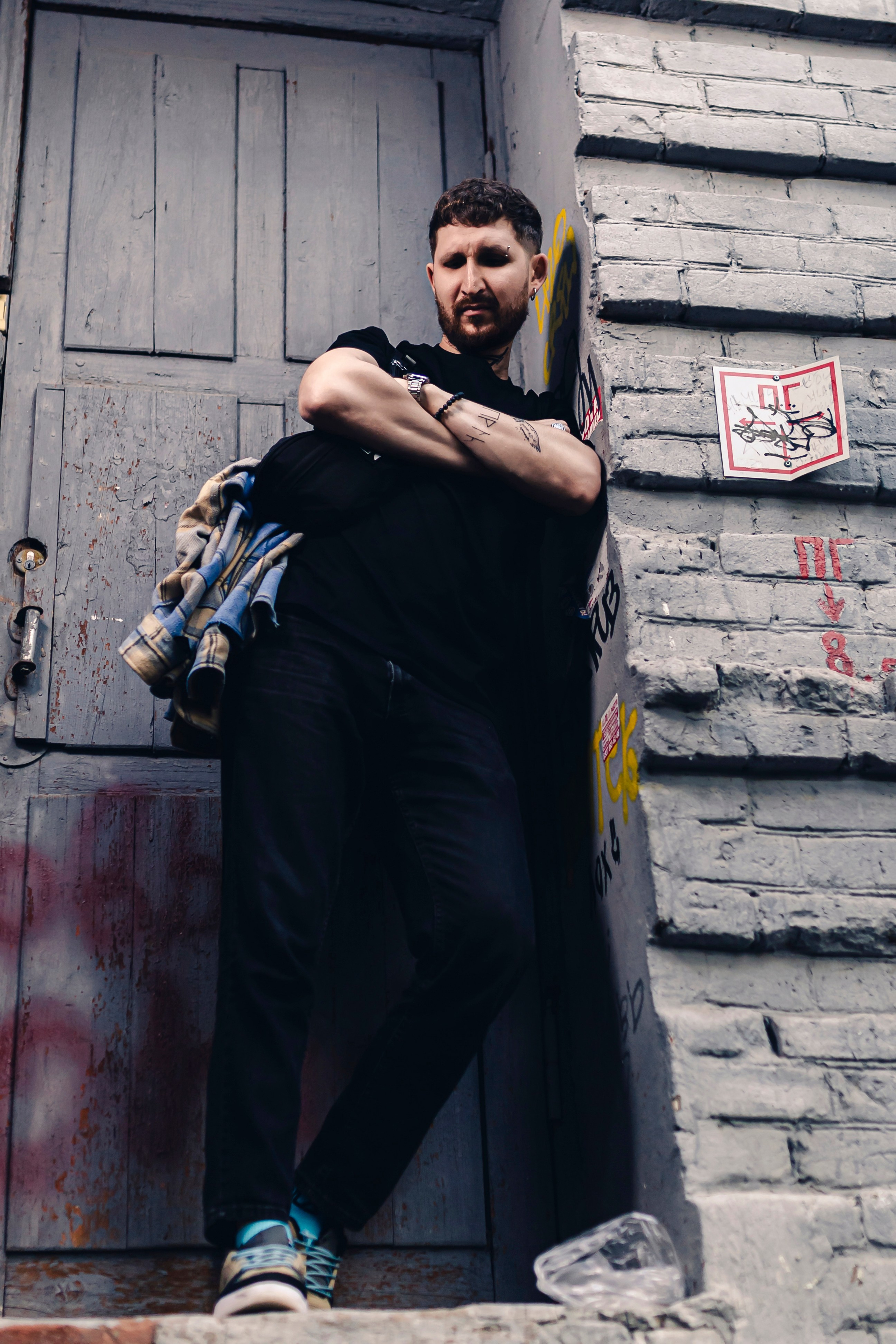 Парень стоит облокотившись на стену 