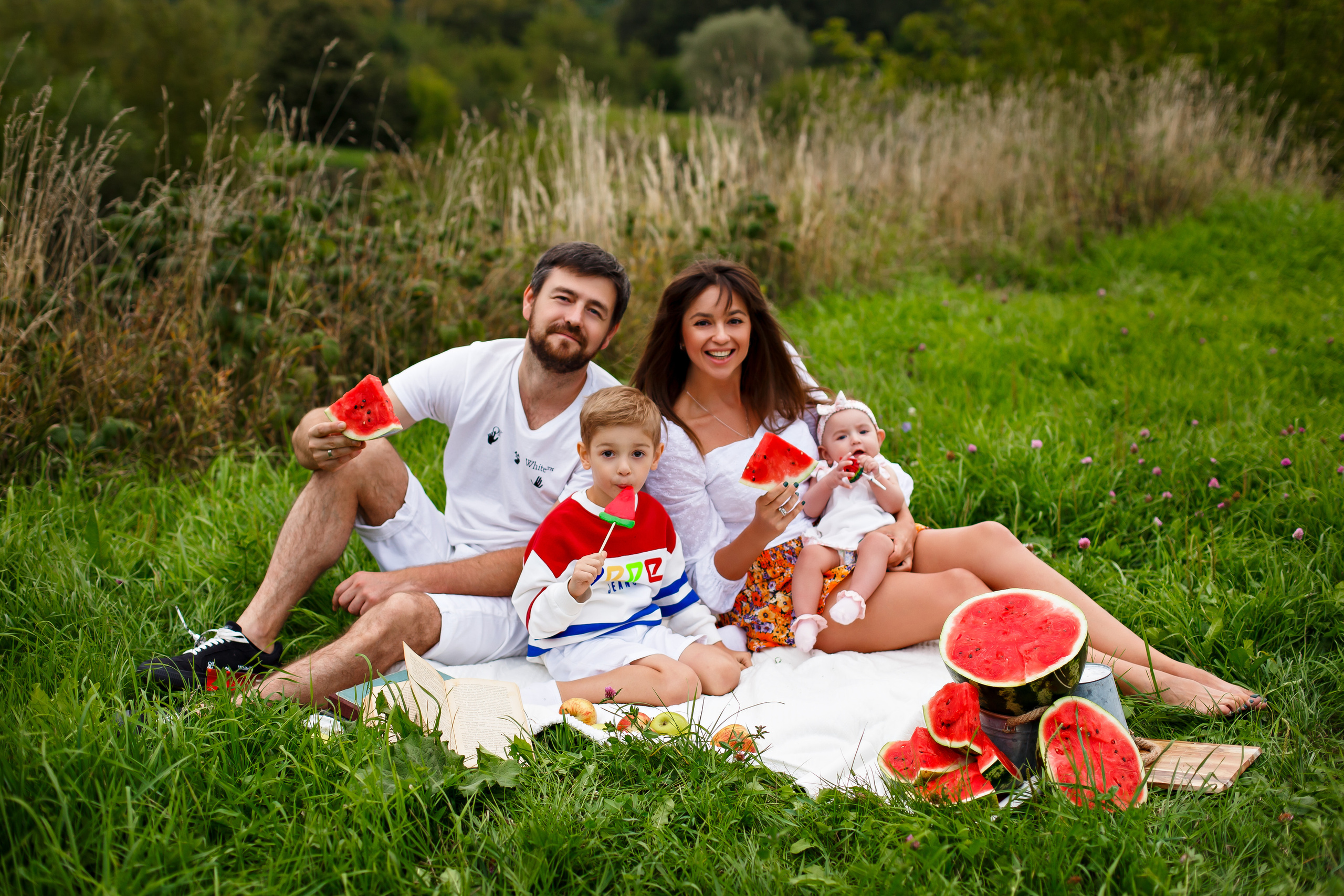 Семья летом на траве едят арбуз 
