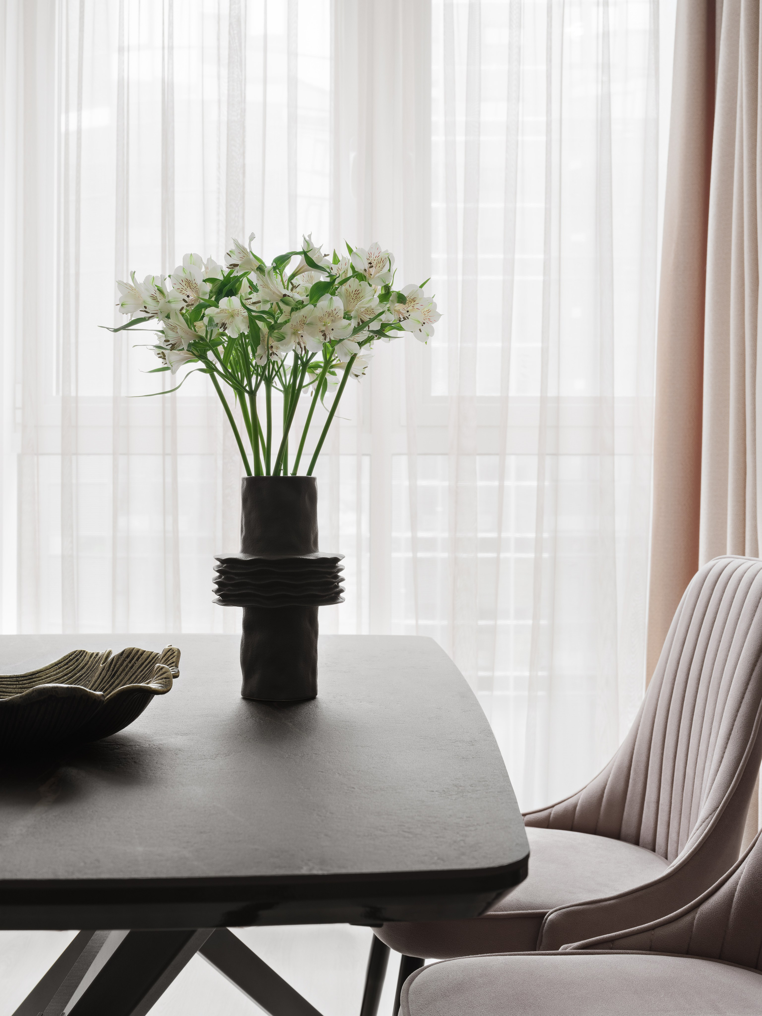 Современный дизайн интерьера спальни и столовой, фото уютного стиля с элегантным черным столом, вазой с белыми цветами и мягким дневным светом, реализованный дизайнером Ольгой Рубченко, стилист Екатерина Ракитина, фото Сергей Денисенко.