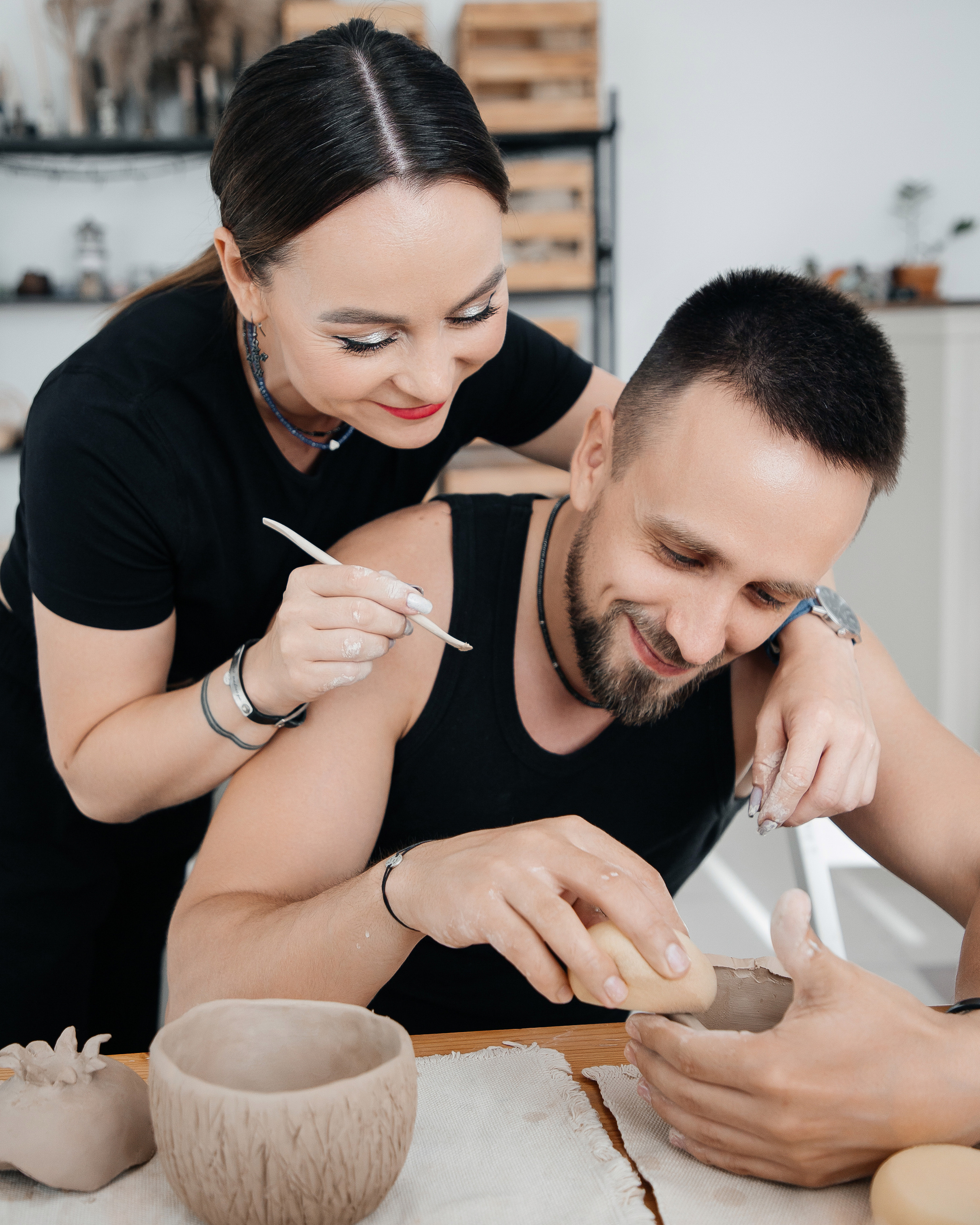 Парный мастеркласс по гончарному мастерству. Мужчина лепит из глины а его невеста ему помогает.