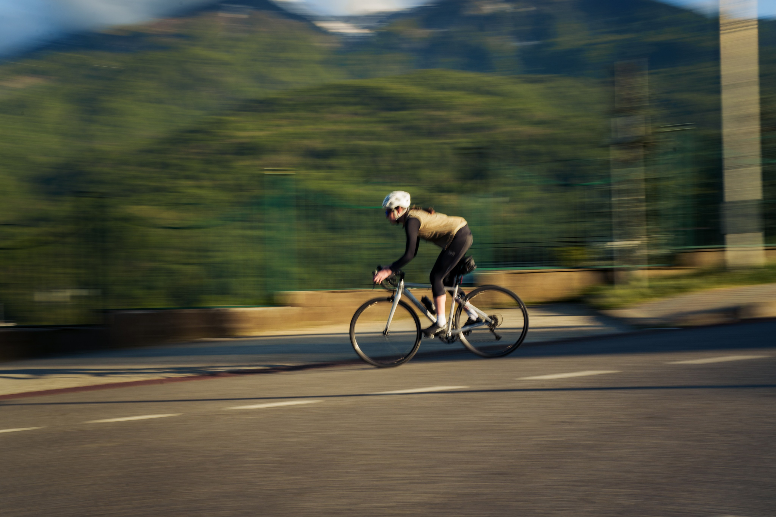 девушка едет на шоссейном велосипеде по горному серпантину