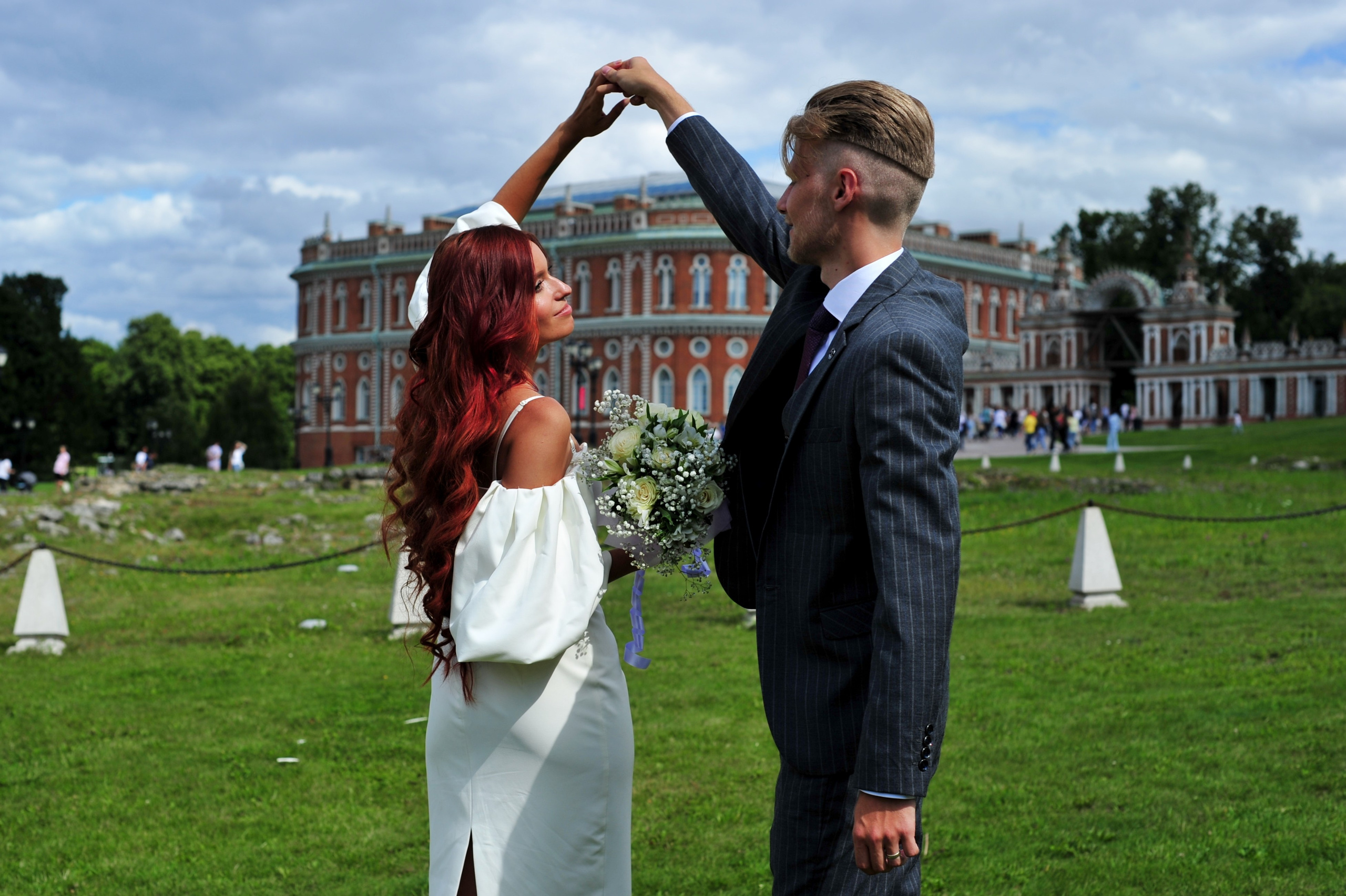 Свадьба в Царицыно летом, жених и невеста держатся за руки