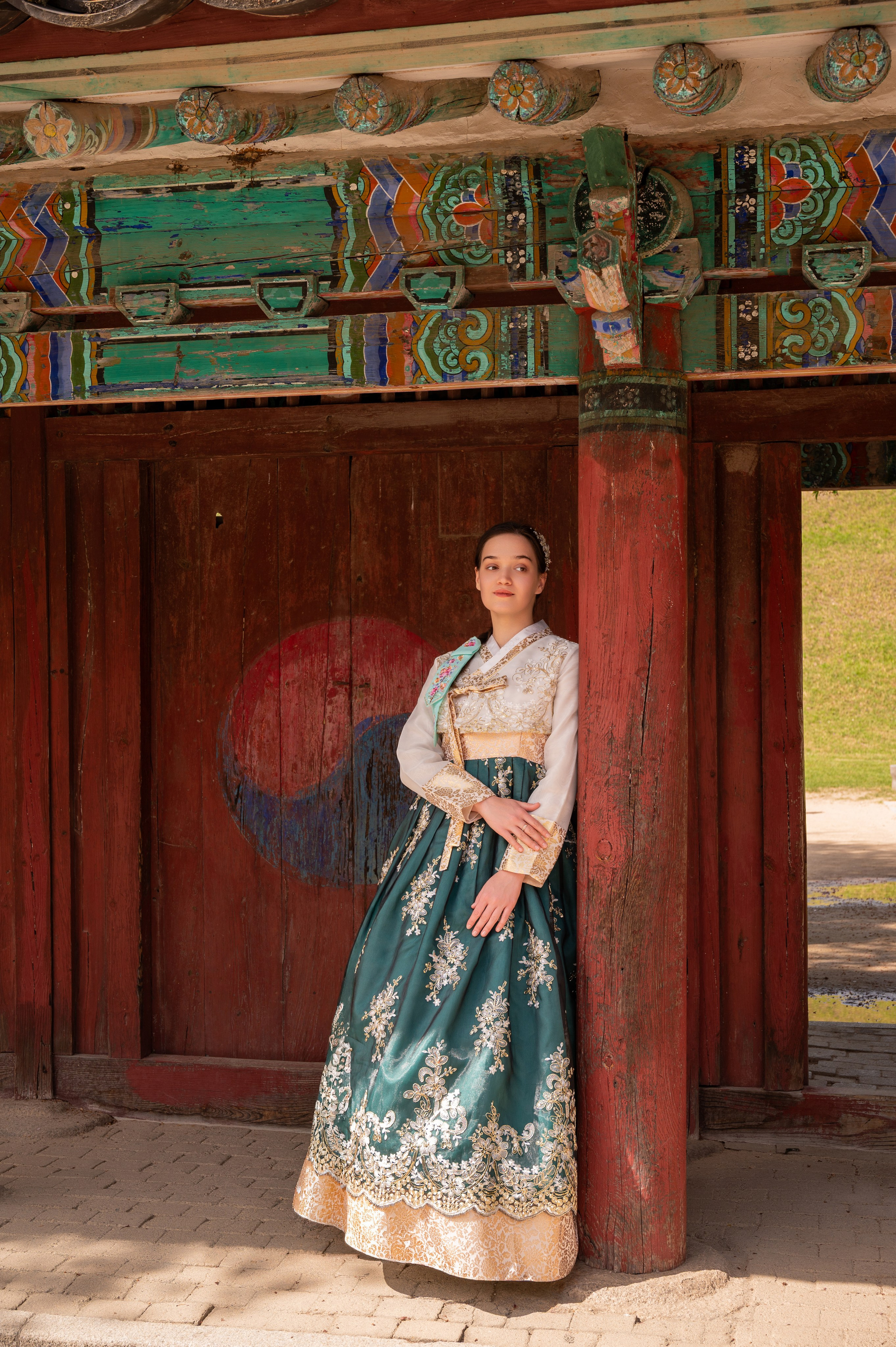 Woman in a green hanbok by red traditional gates — hanbok photoshoot in Busan · 감천문화마을