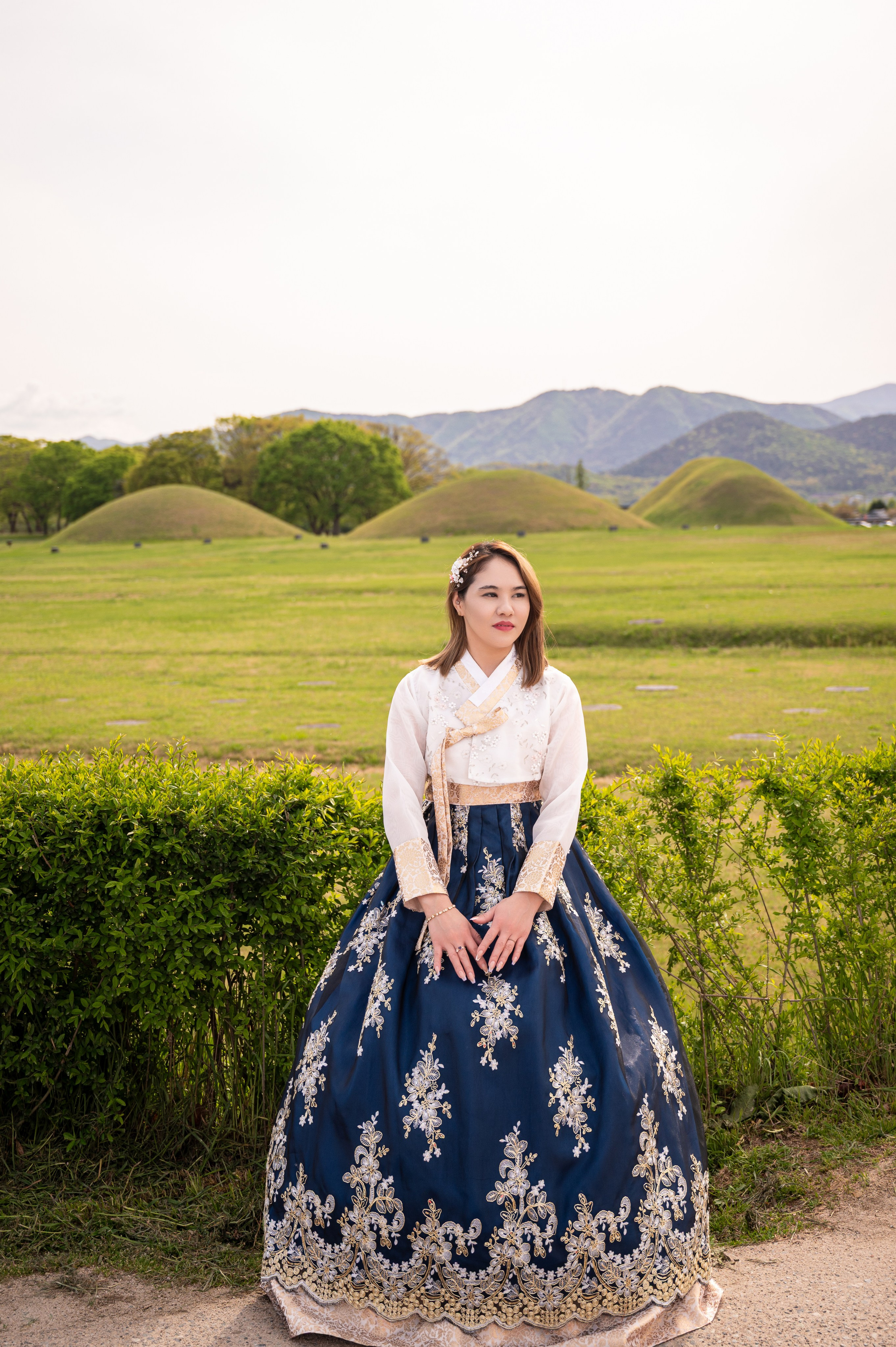Woman in a navy hanbok by the ancient royal tombs of Daereungwon in Gyeongju — hanbok photoshoot · 釜山韩服写真