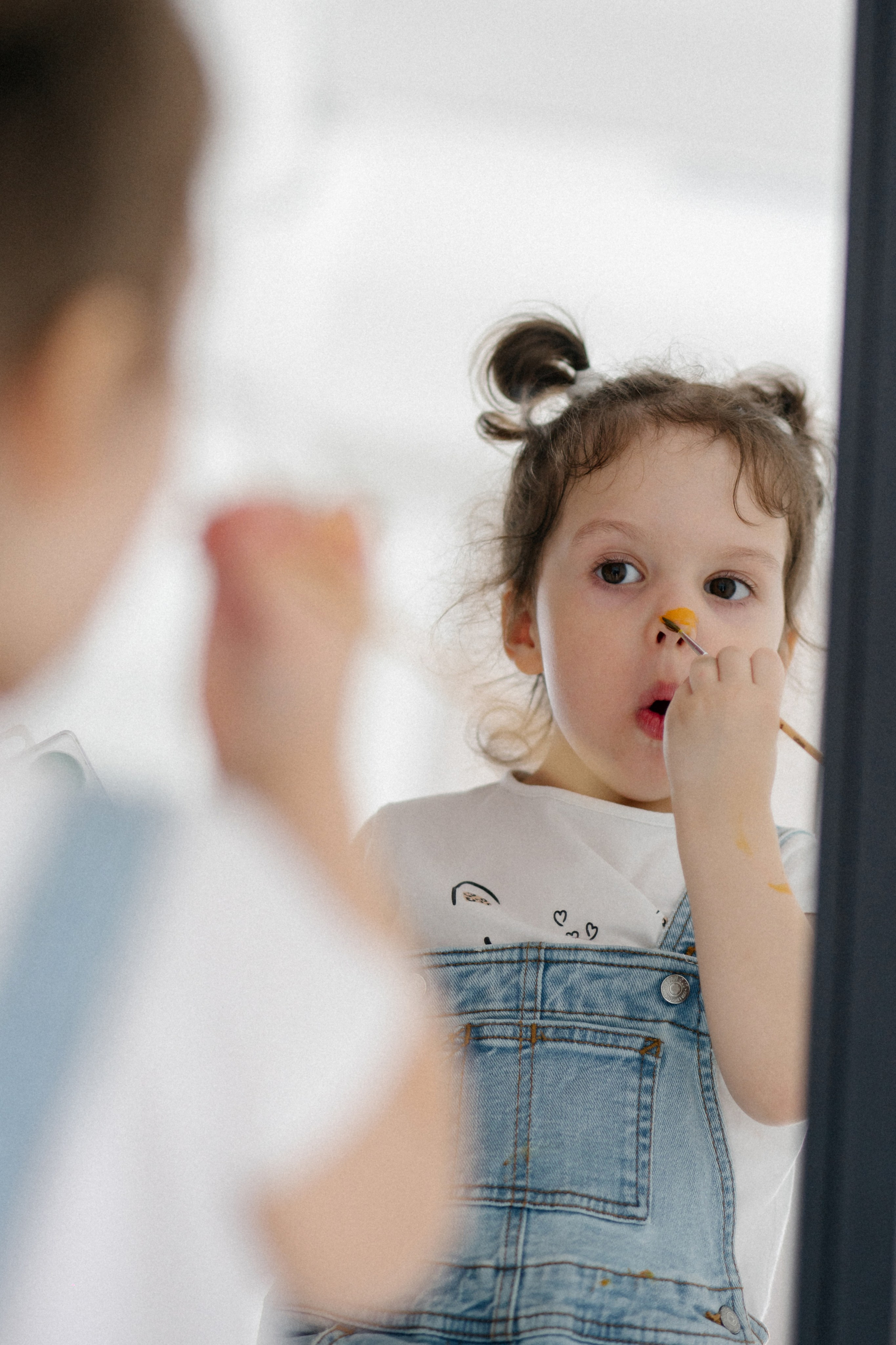 Беззаботность детских фантазий сливается с домашними эмоциями материнства: девочки резво рисуют красками на своём собственном теле и холсте