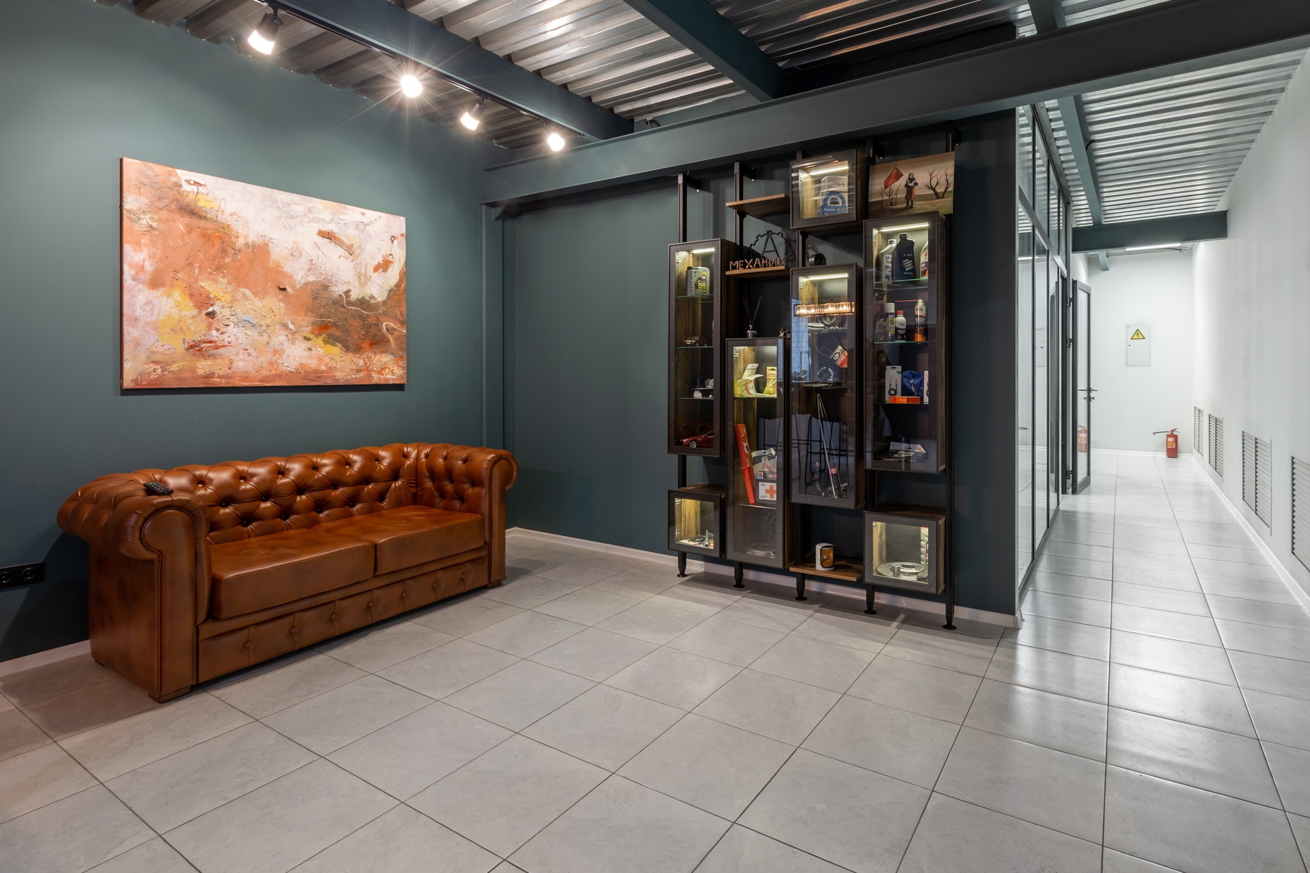 Красивый холл в автосервисе. Коричневый кожаный диван и шкаф в холле авторемонта.