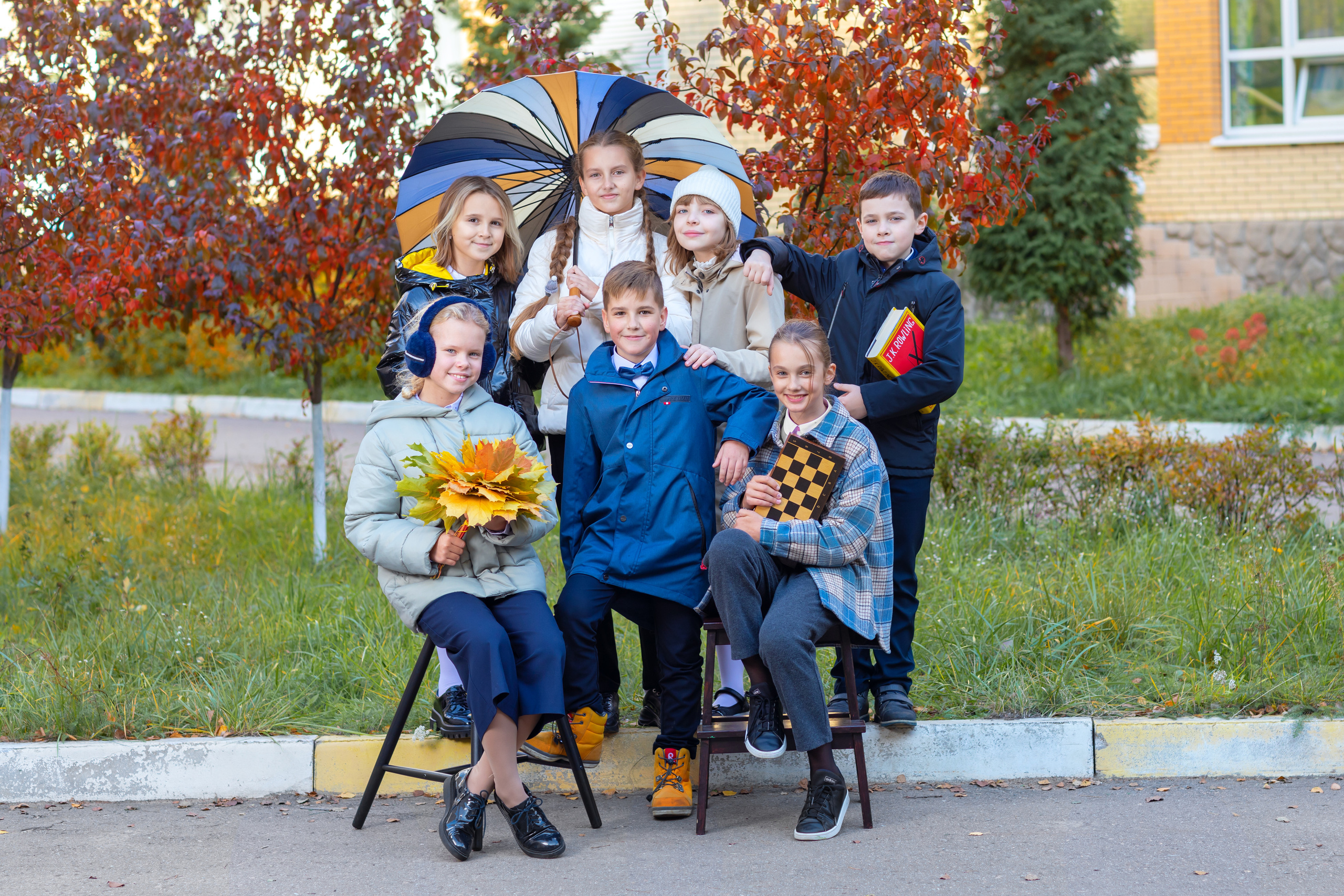 Группа детей позирует осенью во дворе школы